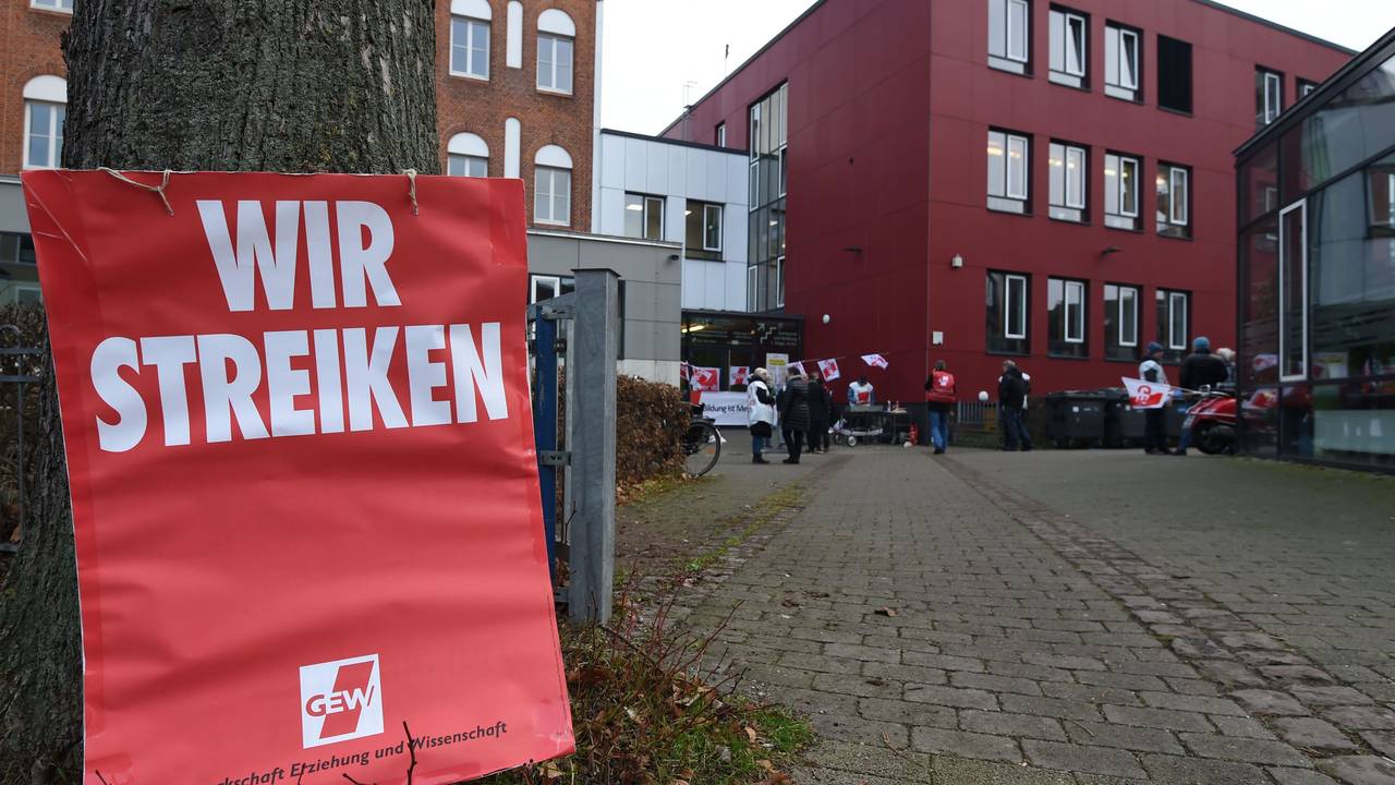 Ein Schild mit "Wir Streiken" lehnt am Eingang zur "Allgemeine Berufsbildende Schule" am Steffensweg an einem Baum.