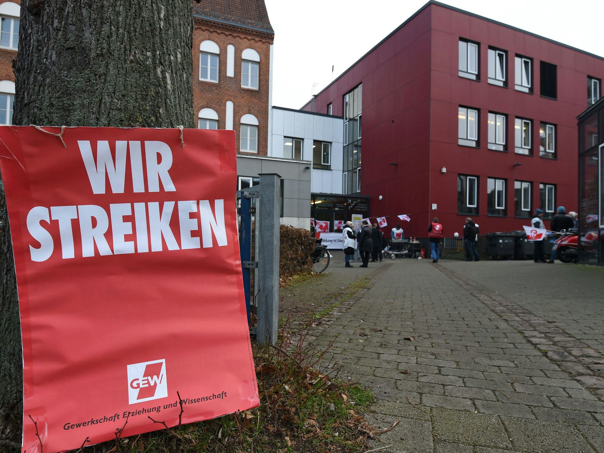 Ein Schild mit "Wir Streiken" lehnt am Eingang zur "Allgemeine Berufsbildende Schule" am Steffensweg an einem Baum.