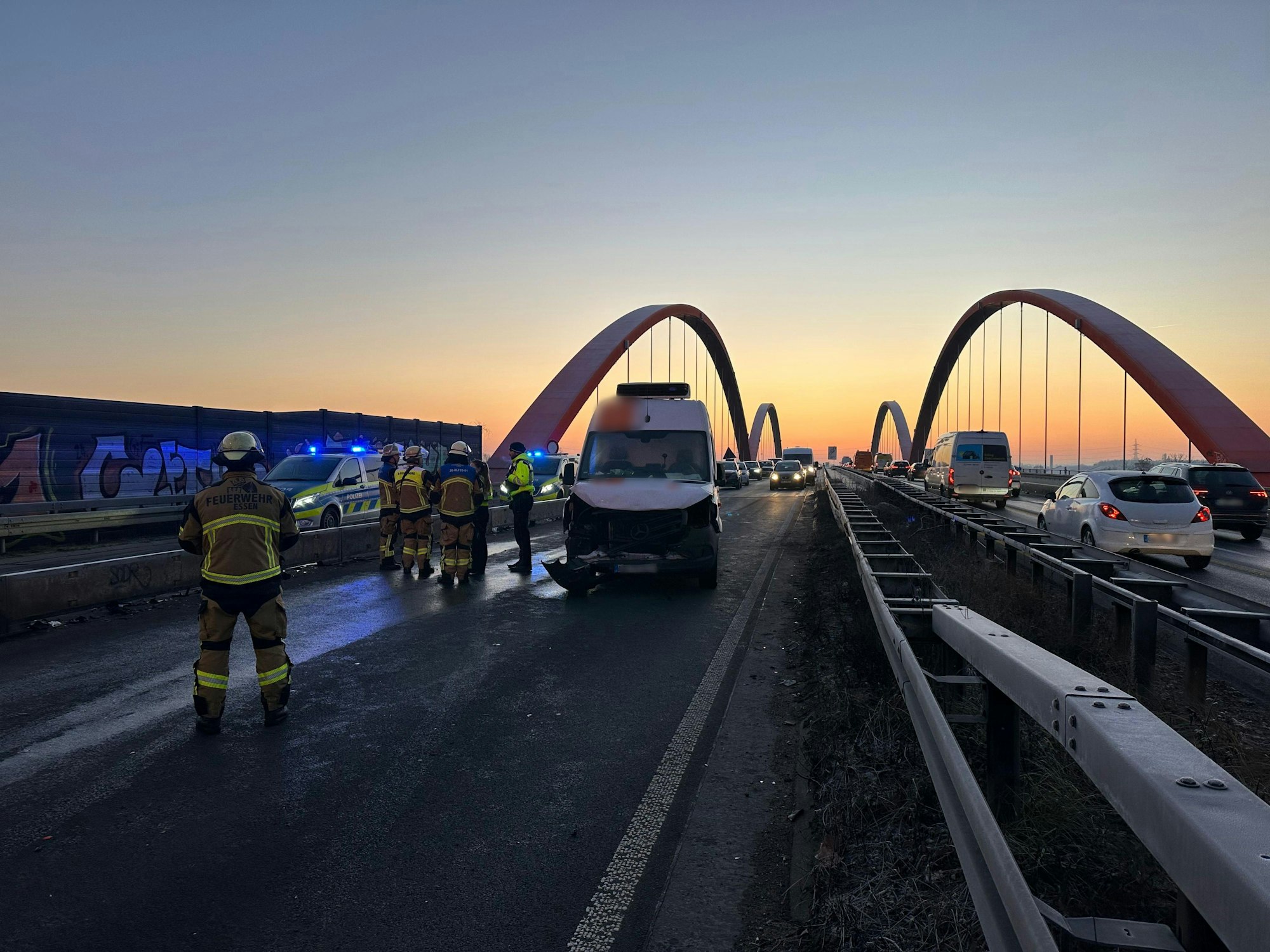 Einsatzkräfte stehen vor einer Brücke auf der Autobahn 42. Auf glatter Fahrbahn sind am Morgen auf der Autobahn 42 zwischen Essen und Bottrop 19 Fahrzeuge kollidiert.