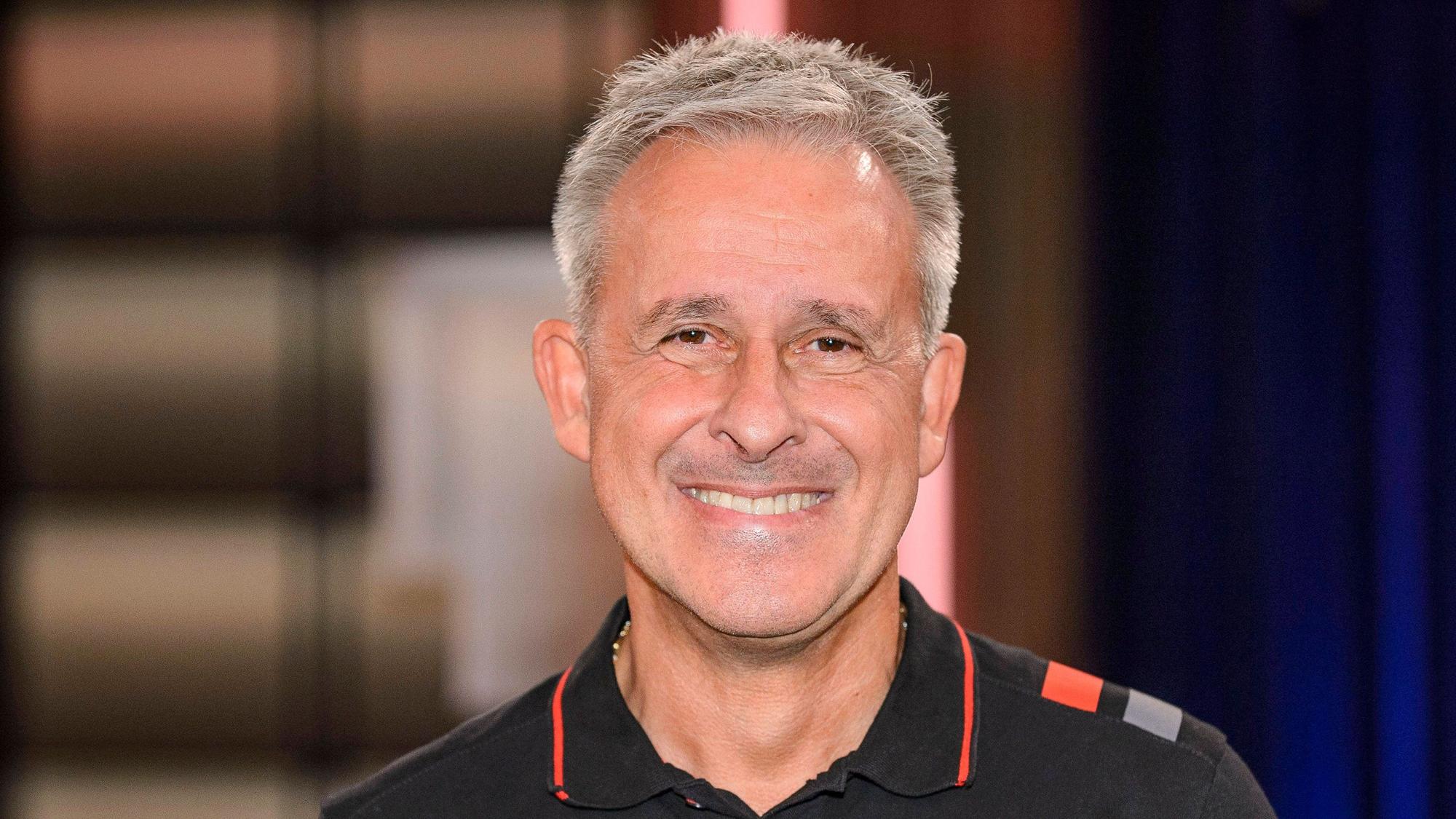 Pierre Littbarski lächelt für ein Foto in die Kamera.