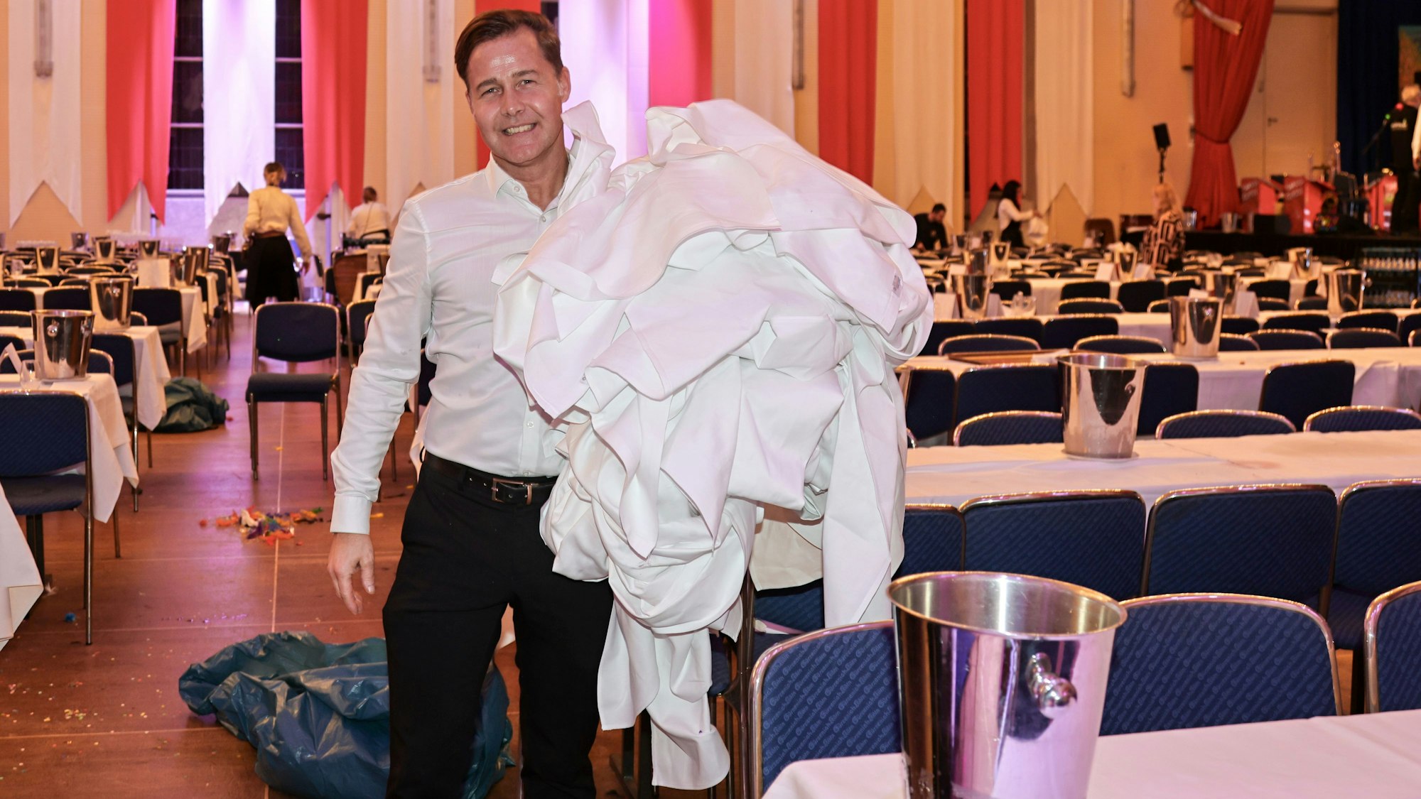 Ein Mitarbeiter sammelt schmutzige Tischdecken ein.