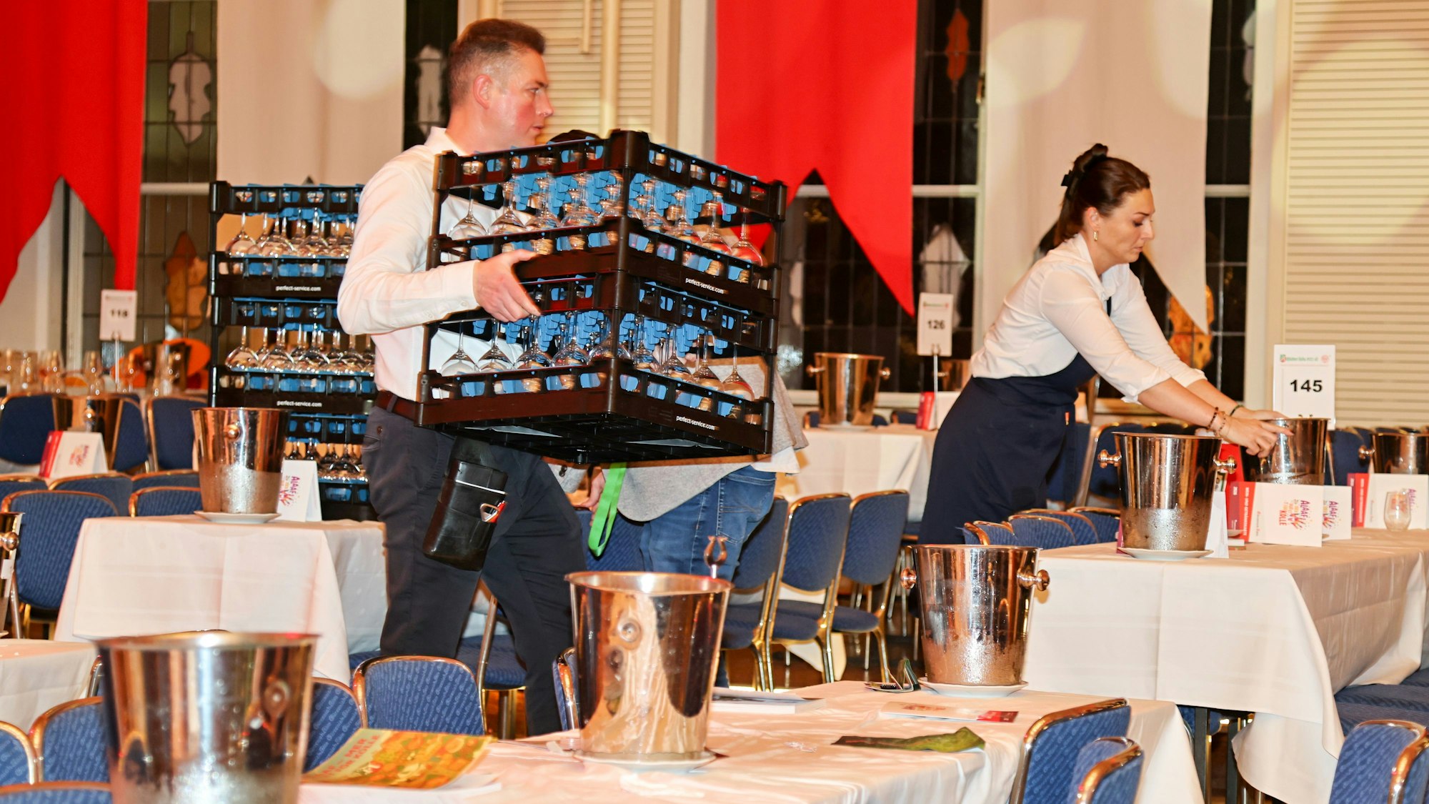 Ein Mitarbeiter bringt neue Weingläser zu den Tischen.