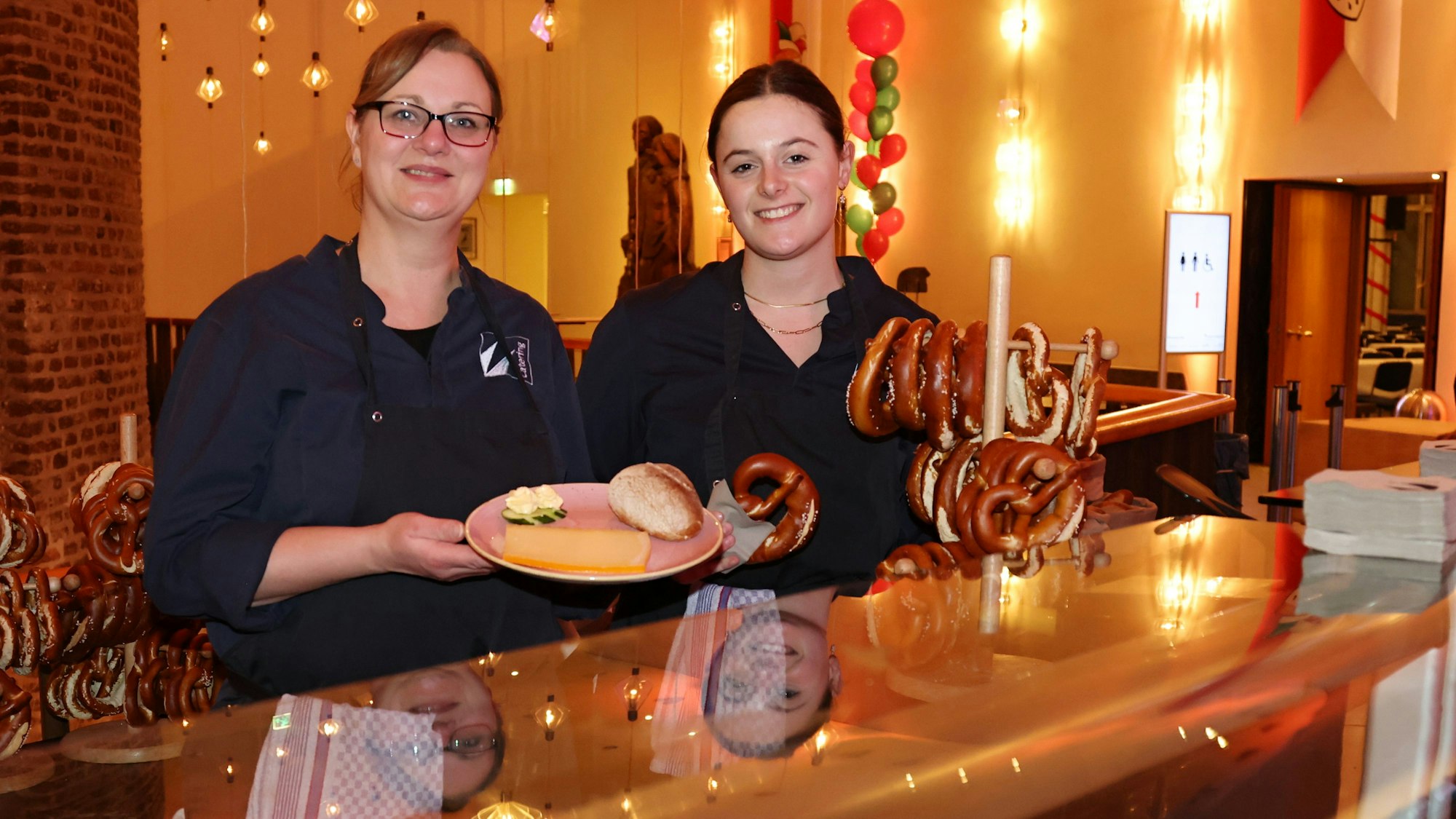 Mitarbeiterinnen präsentieren das Essen hinter der Theke.