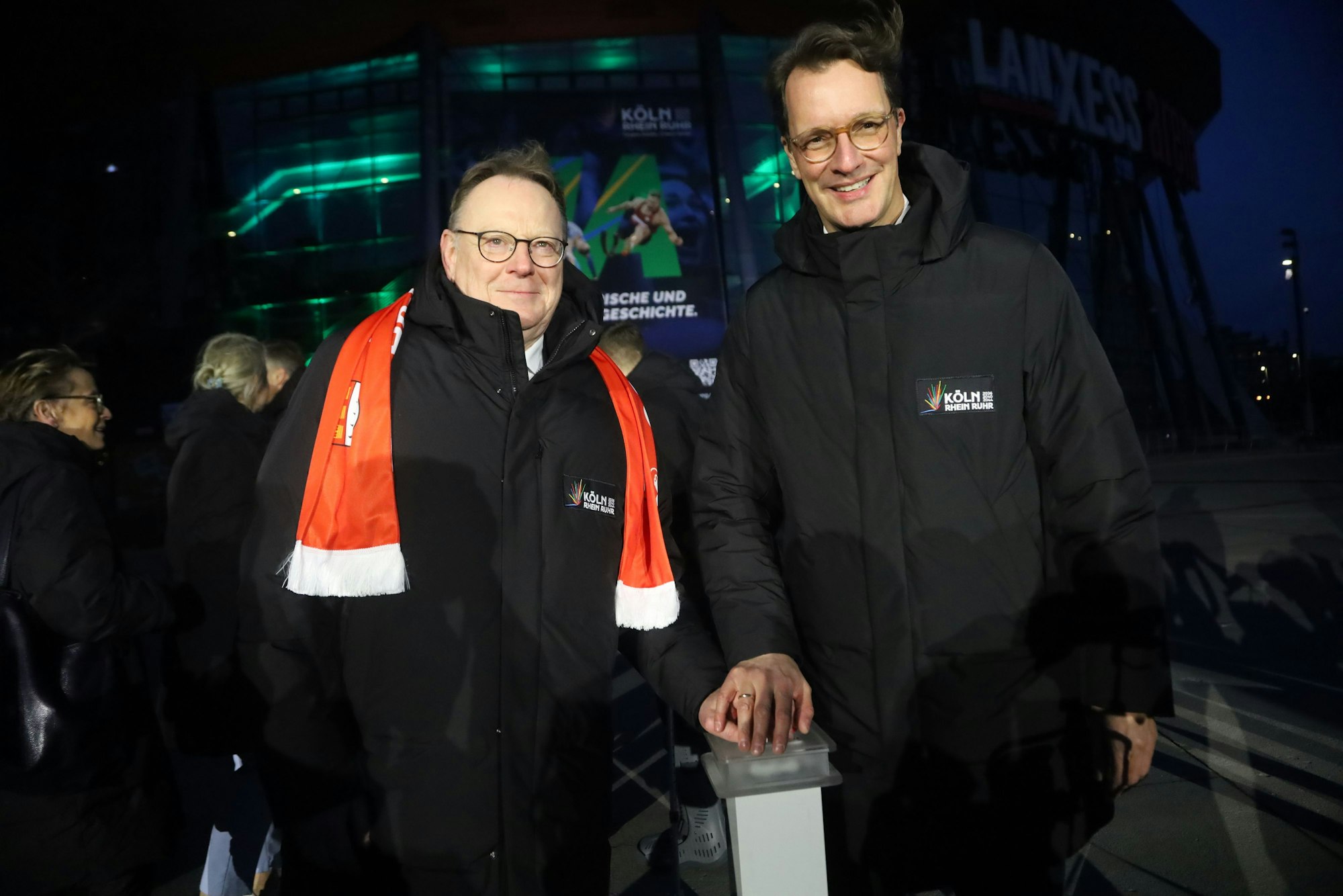 Ministerpräsident Hendrik Wüst (r.) und OB Torsten Burmester drücken symbolisch einen Knopf, der zeitgleich Lichtinstallationen an markanten Orten in NRW aktiviert.