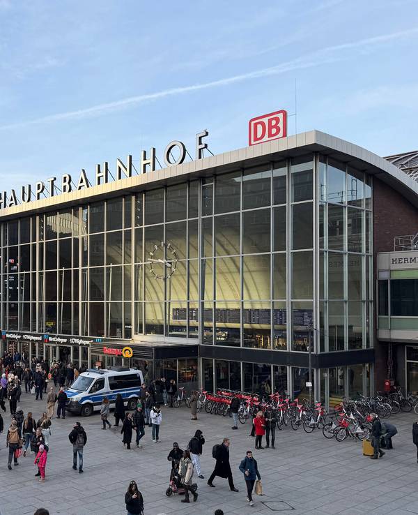 Bahnhofsvorplatz mit Menschen, Gebäude und Kirche