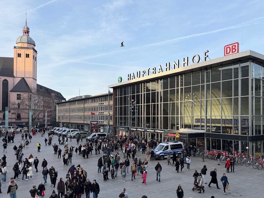 Bahnhofsvorplatz mit Menschen, Gebäude und Kirche
