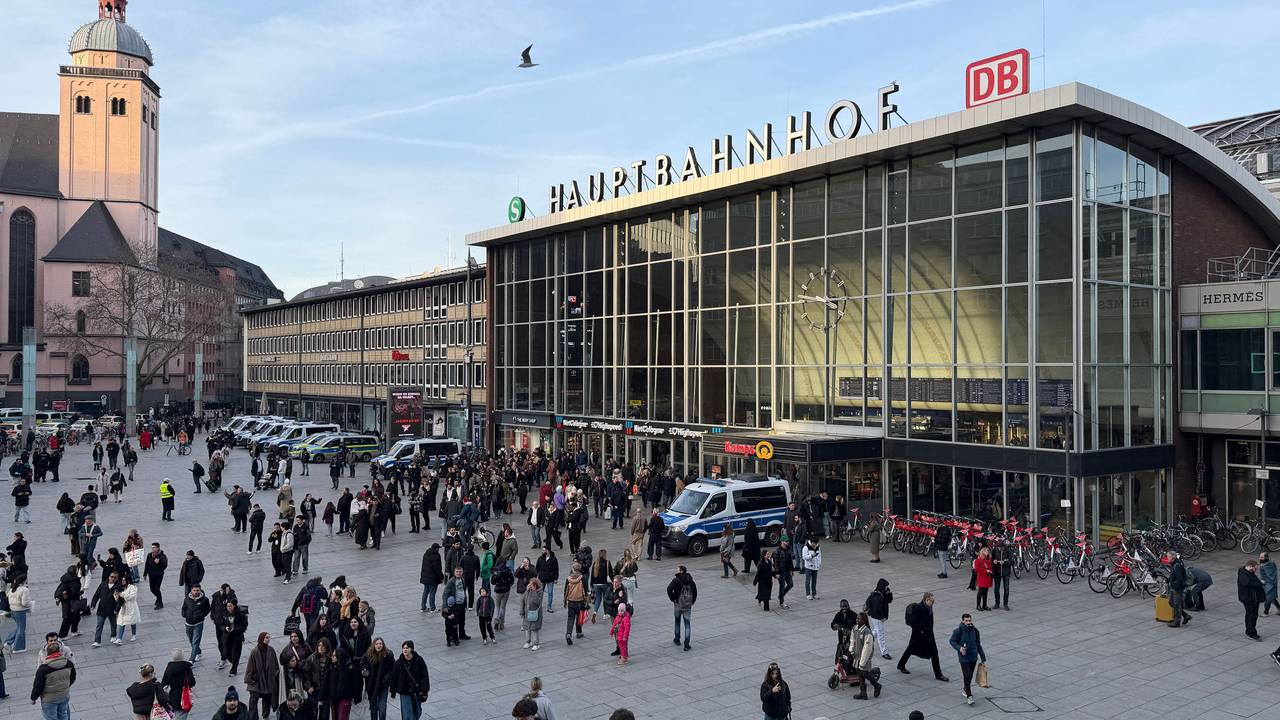 Bahnhofsvorplatz mit Menschen, Gebäude und Kirche