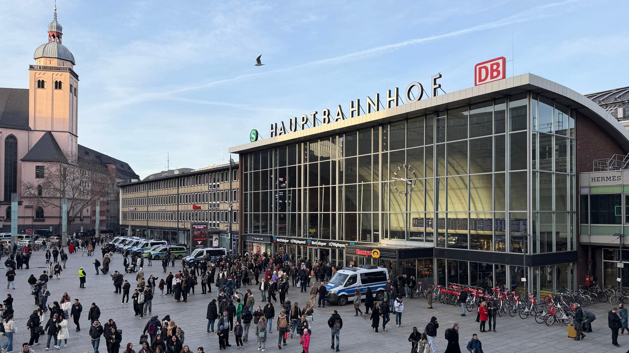 Bahnhofsvorplatz mit Menschen, Gebäude und Kirche