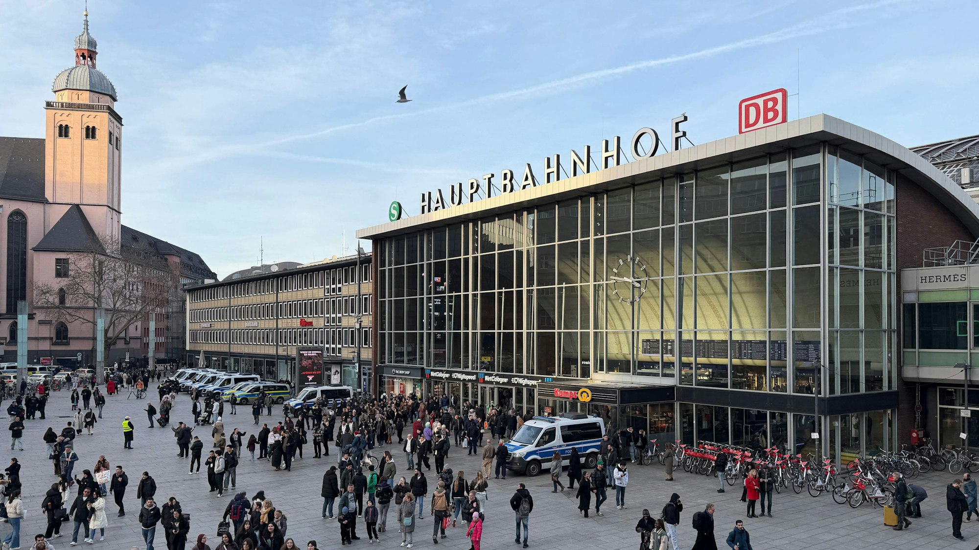 Bahnhofsvorplatz mit Menschen, Gebäude und Kirche