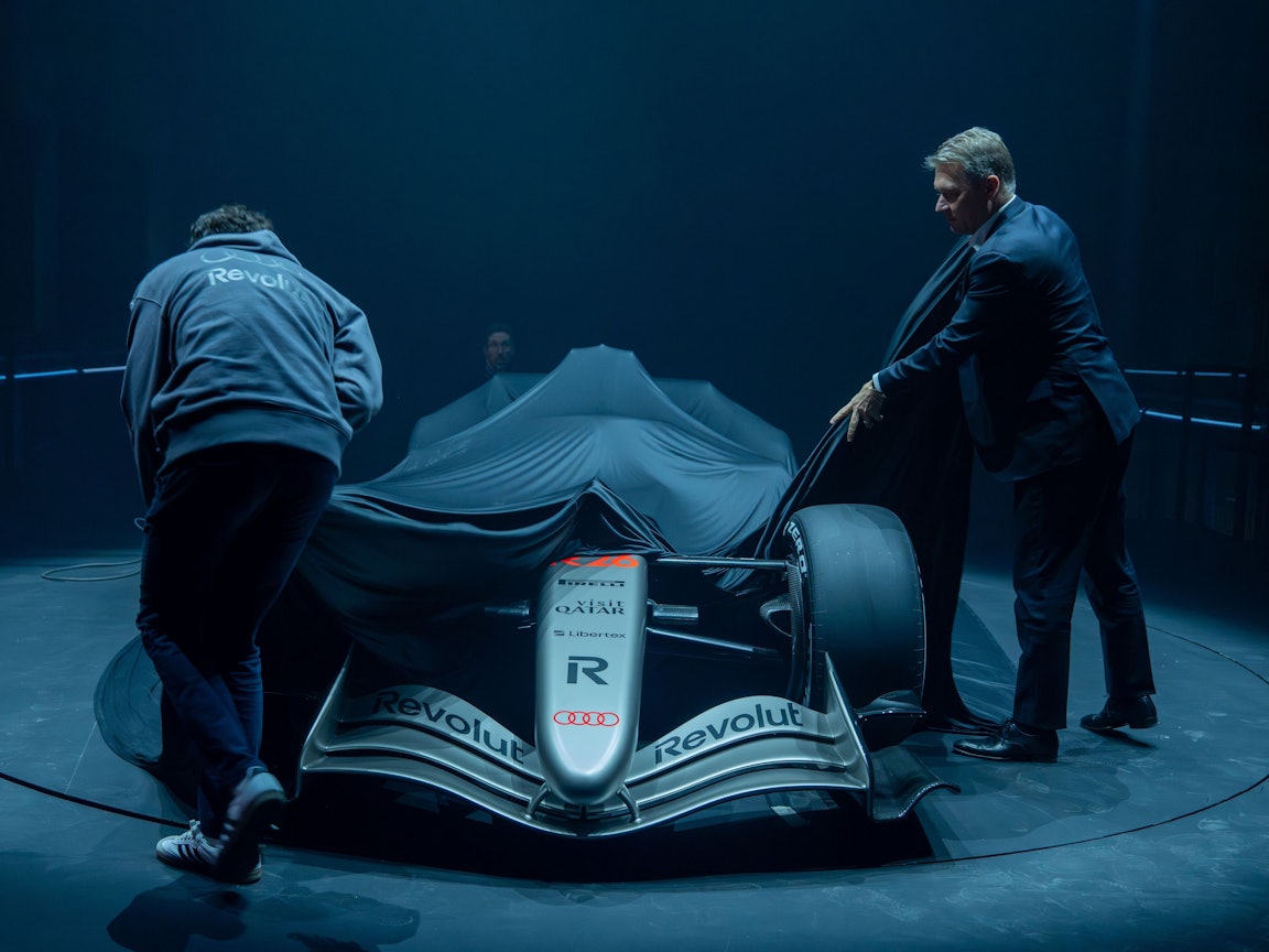 Gernot Döllner (r), Vorstandsvorsitzender der Audi AG, und ein Mitarbeiter ziehen die Plane von dem Formel-1-Rennwagen R 26 von Audi Revolut, der während der Vorstellung des Fahrzeuges im Kraftwerk Mitte auf einer Bühne steht.