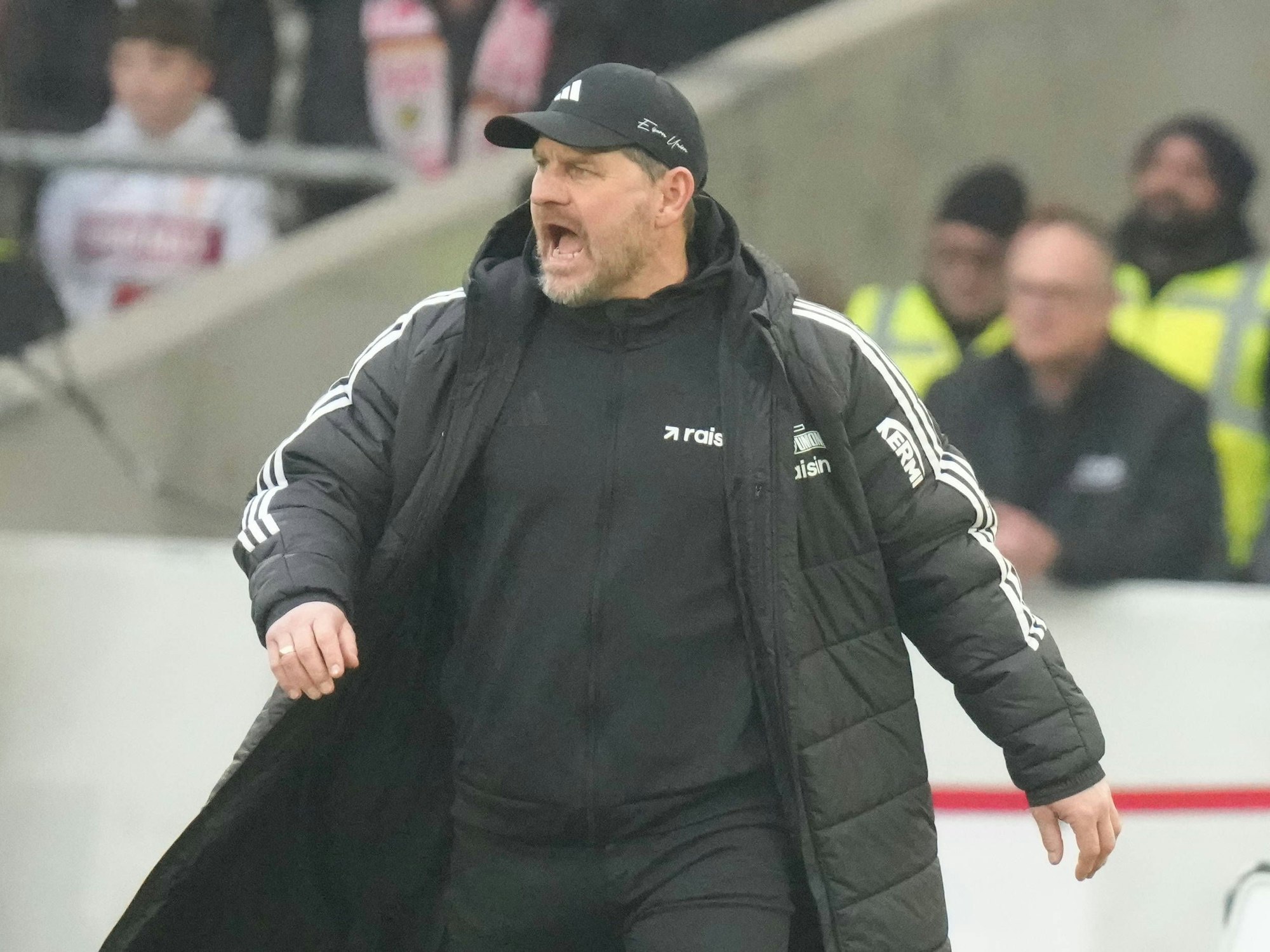 Steffen Baumgart schreit etwas von der Seitenlinie auf den Platz, dabei trägt er eine schwarze Jacke.