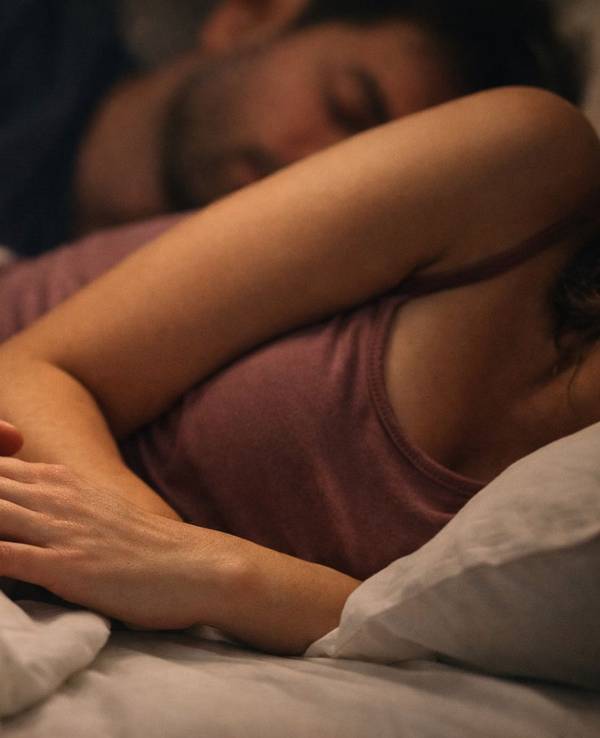 Paar liegt kuschelnd im Bett und schläft.