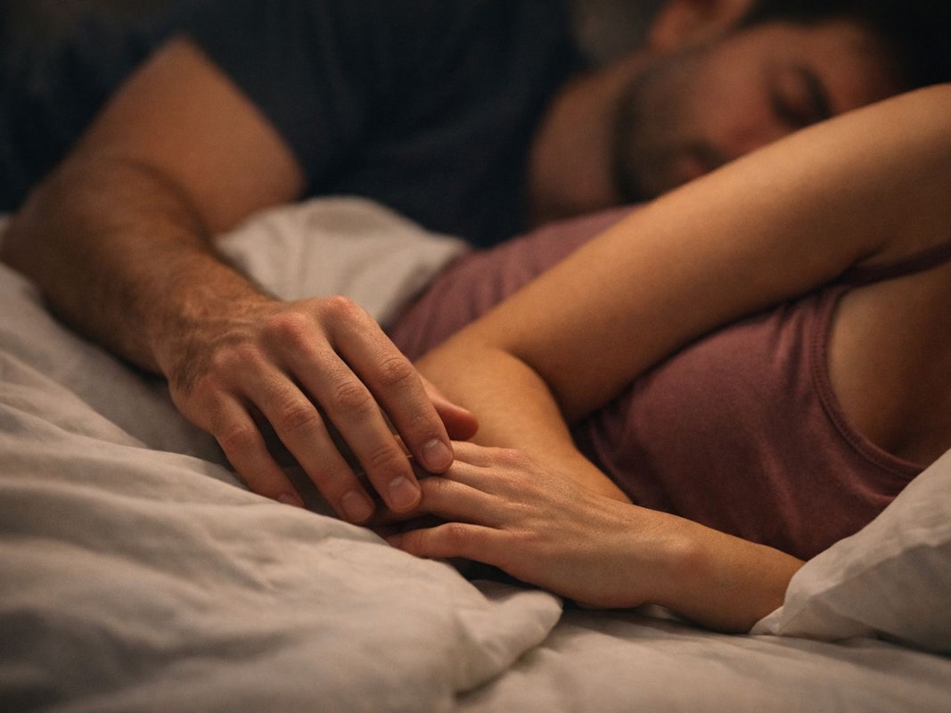 Paar liegt kuschelnd im Bett und schläft.