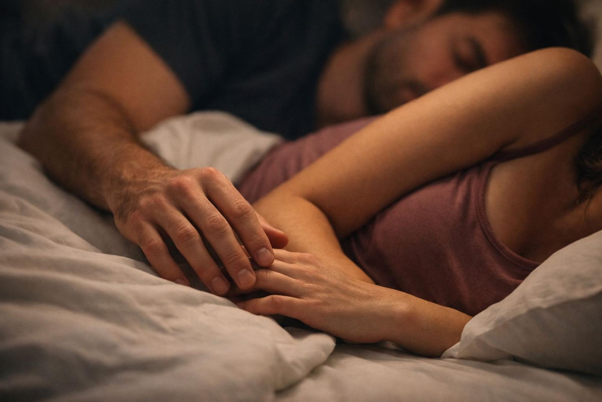 Paar liegt kuschelnd im Bett und schläft.