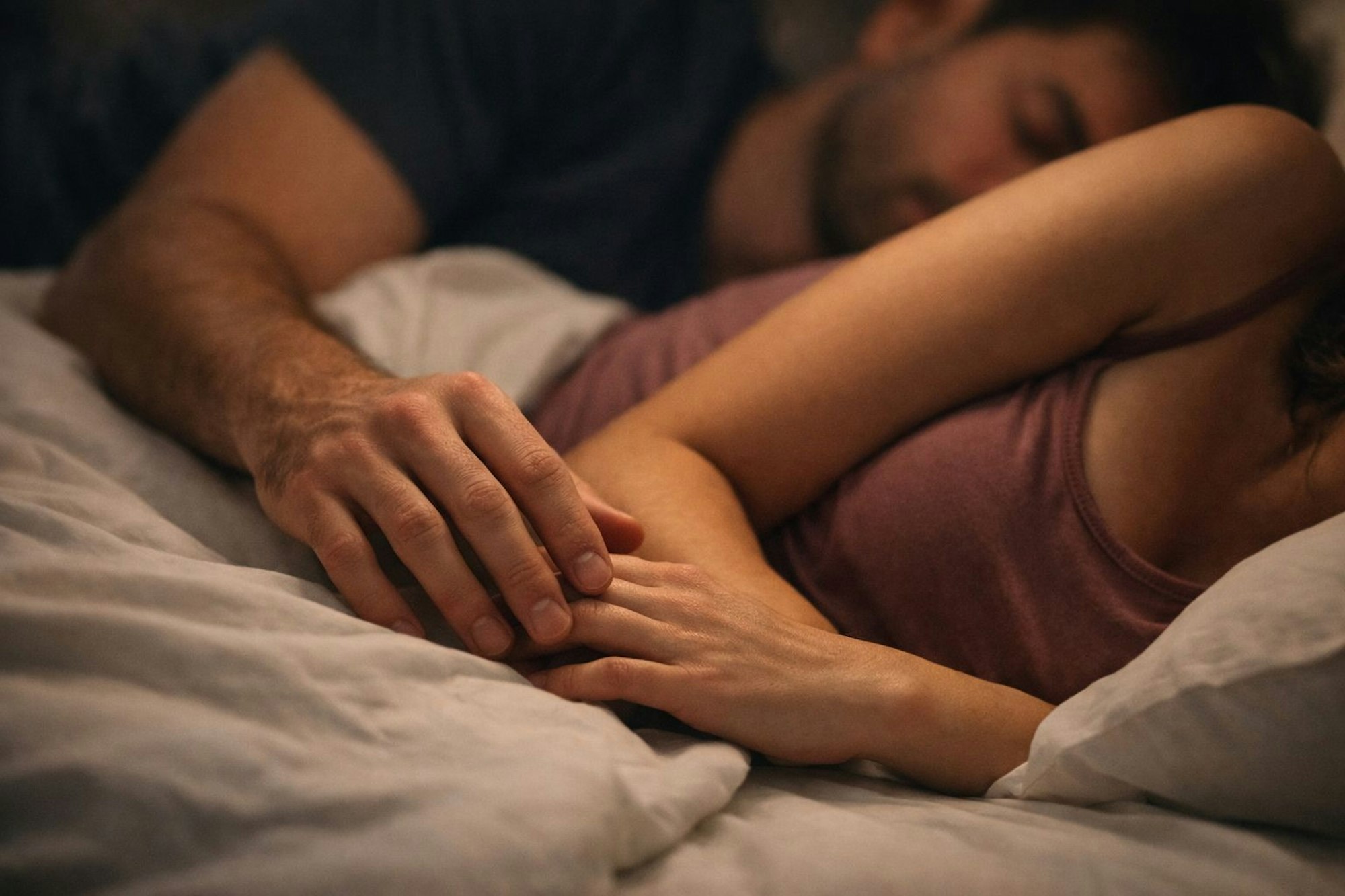 Paar liegt kuschelnd im Bett und schläft.