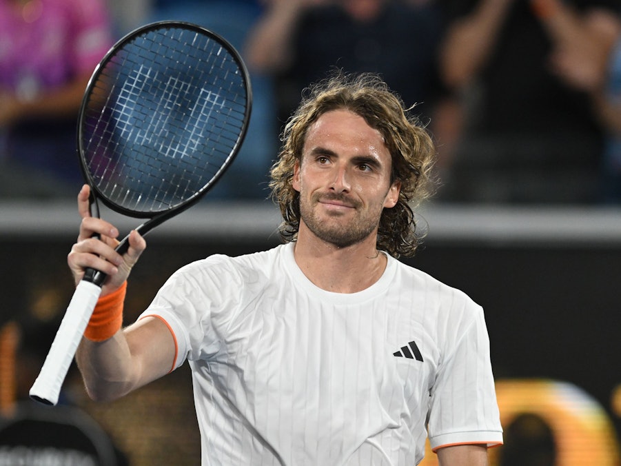 Stefanos Tsitsipas hält Tennisschläger und lächelt