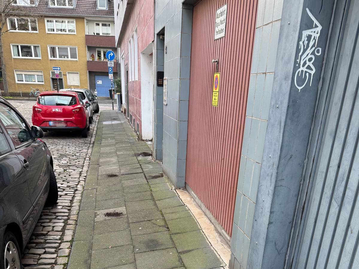 Erdhäufchen verteilen sich auf einem Gehweg vor Garageneinfahrten.