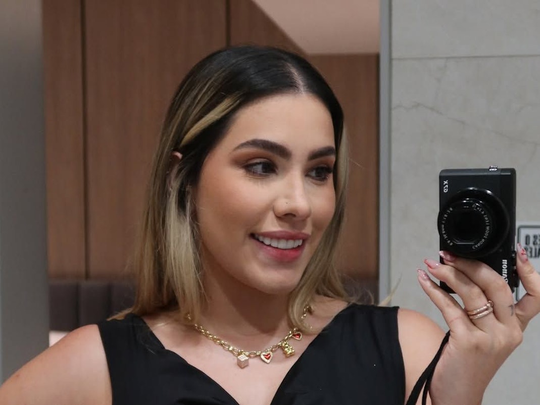 Ana Cardona fotografiert sich mit einer Kamera im Spiegel selbst.