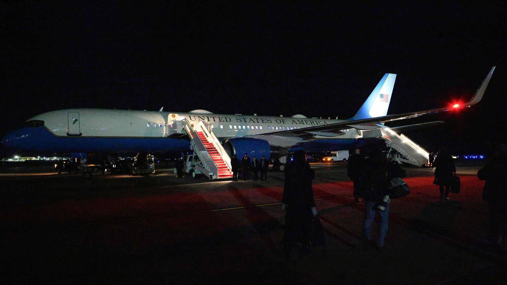 Menschen gehen nachts auf ein Flugzeug zu, das am Boden steht.