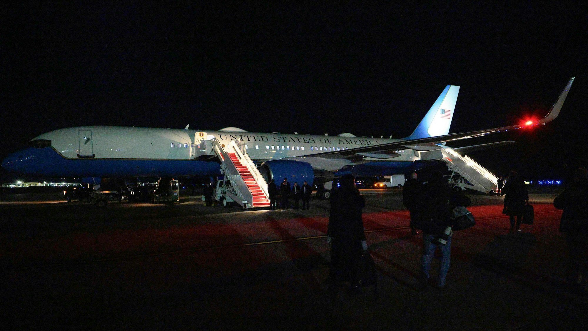 Menschen gehen nachts auf ein Flugzeug zu, das am Boden steht.