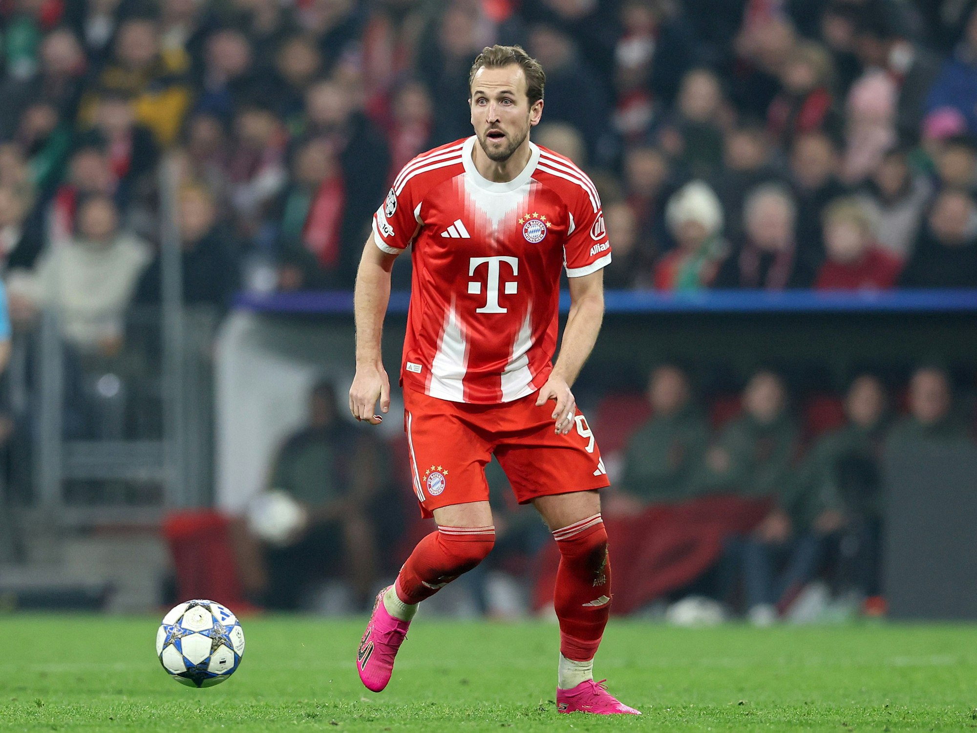 Harry Kane in Aktion auf dem Rasen, vor ihm fliegt der Champions-League-Ball knapp über dem Rasen.