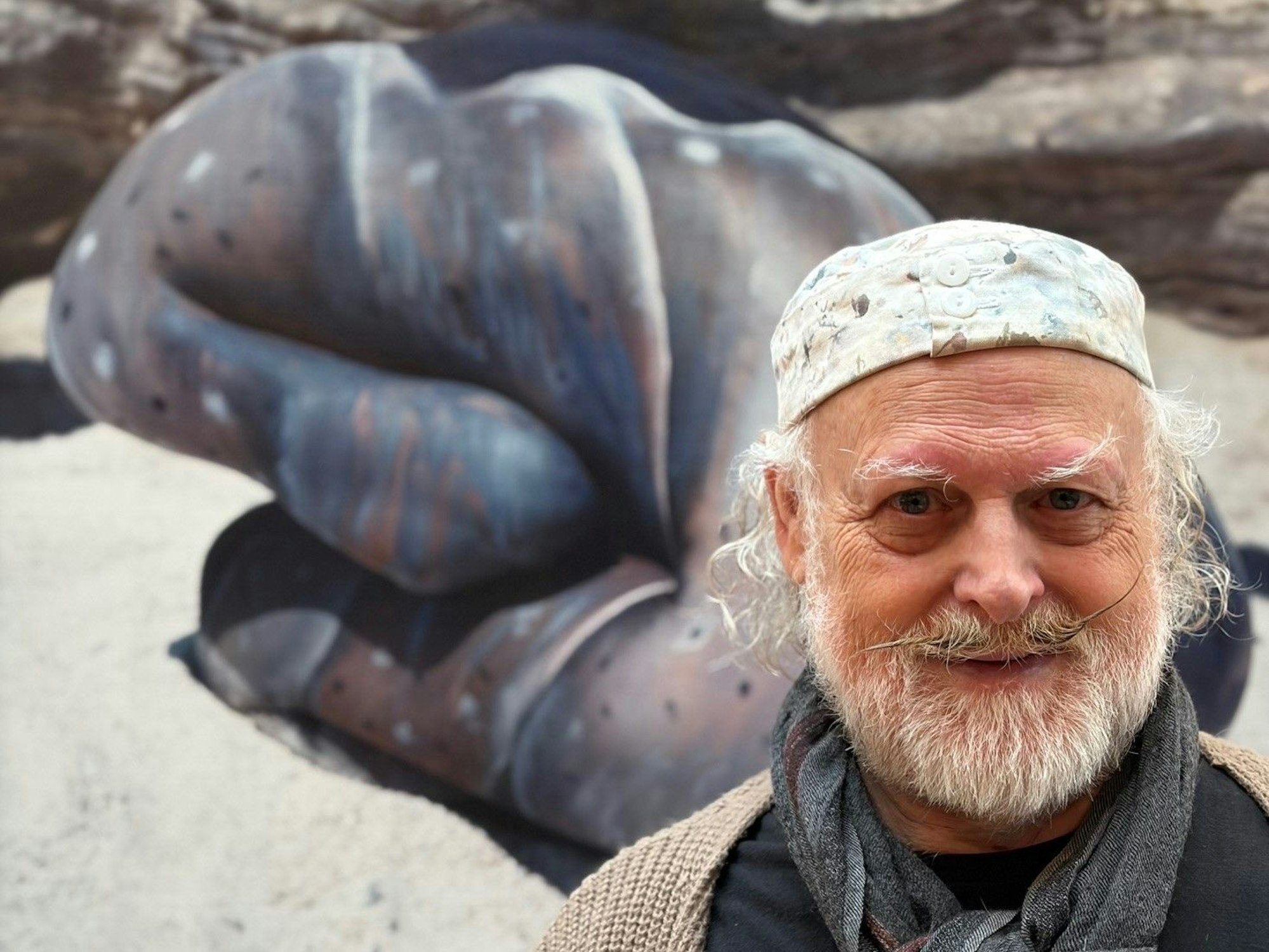 Ein Mann mit Zwirbelbart und kleinem Käppi schaut in die Kamera