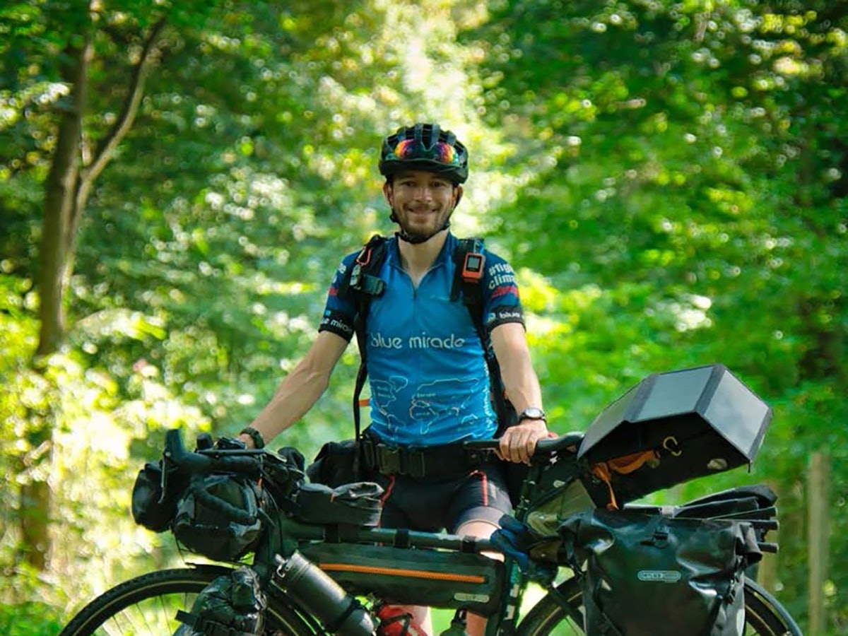 Florian Berg steht neben seinem vollbepackten Fahrrad.