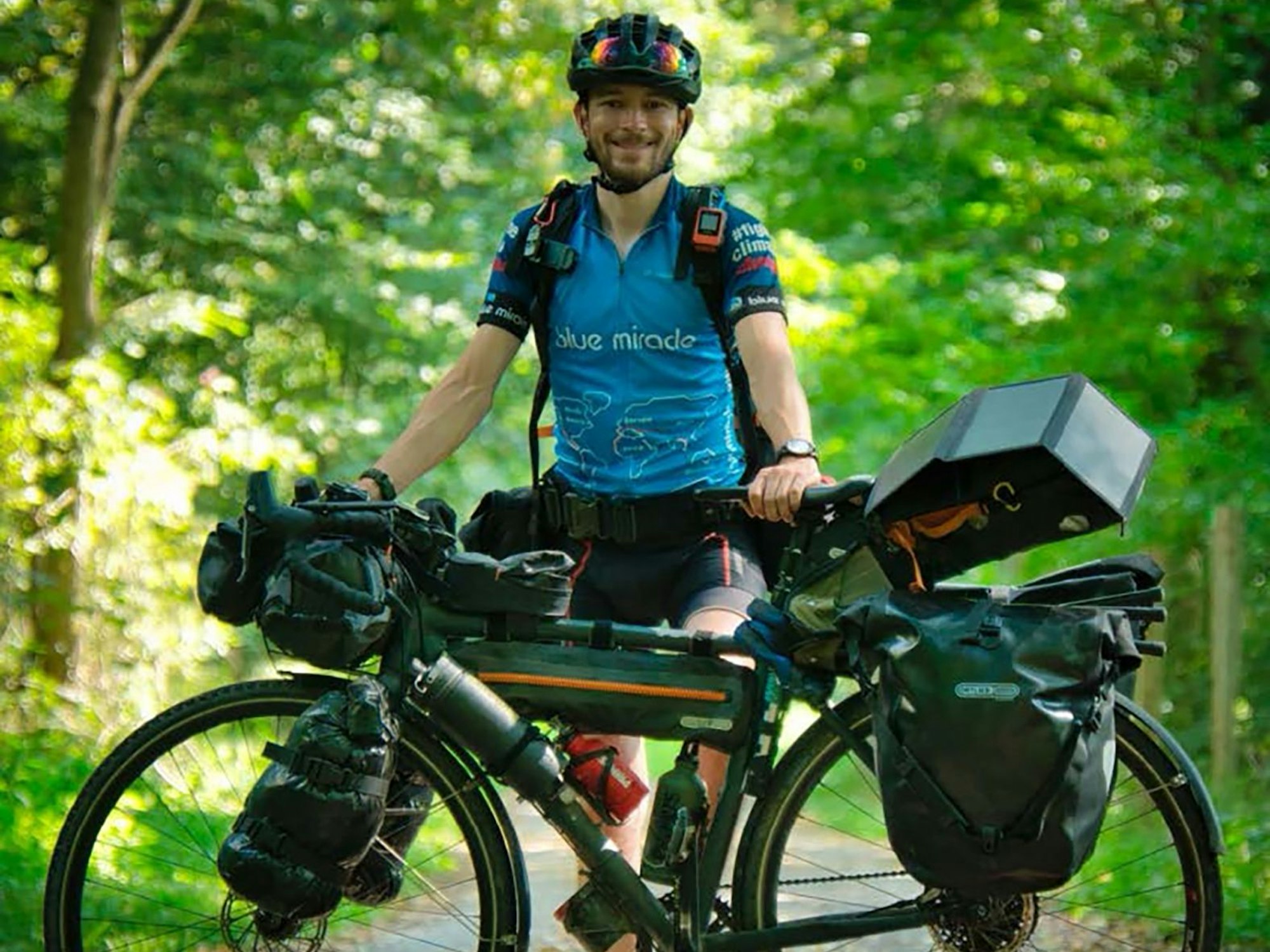 Florian Berg steht neben seinem vollbepackten Fahrrad.