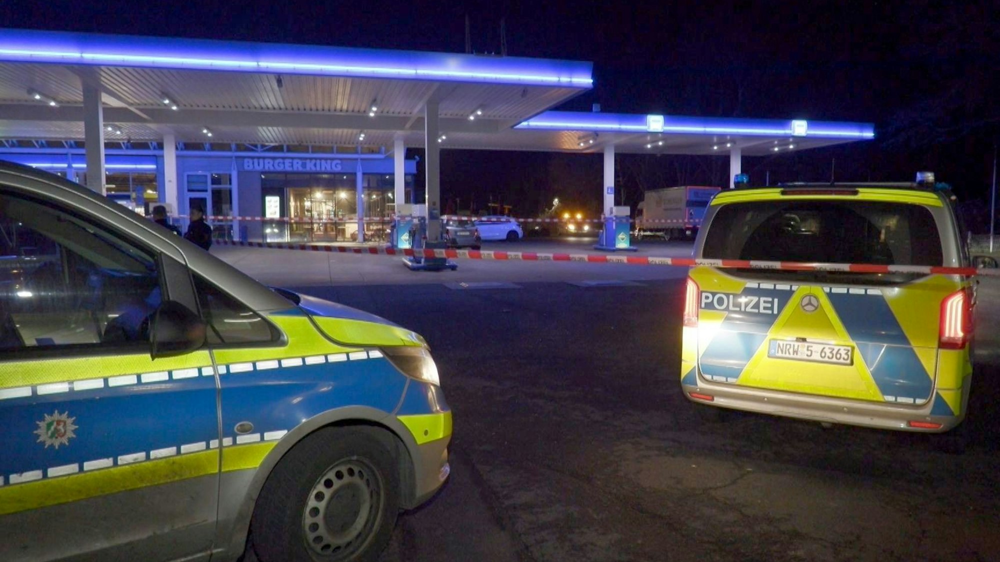 Einsatzwagen der Polizei stehen auf dem Gelände einer Tankstelle.