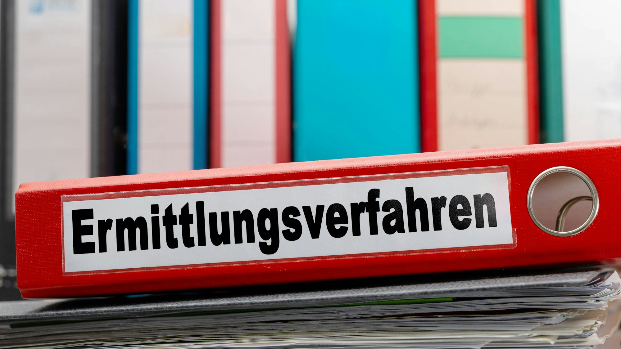 Roter Ordner auf Aktenstapel mit anderen Ordnern