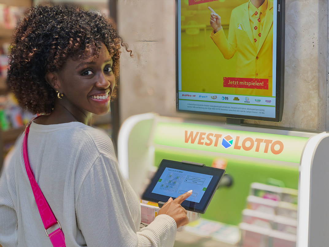 Eine Frau gibt ihren Tipp für das Spiel LOTTO 6aus49 an einem WestLotto Stand ab.