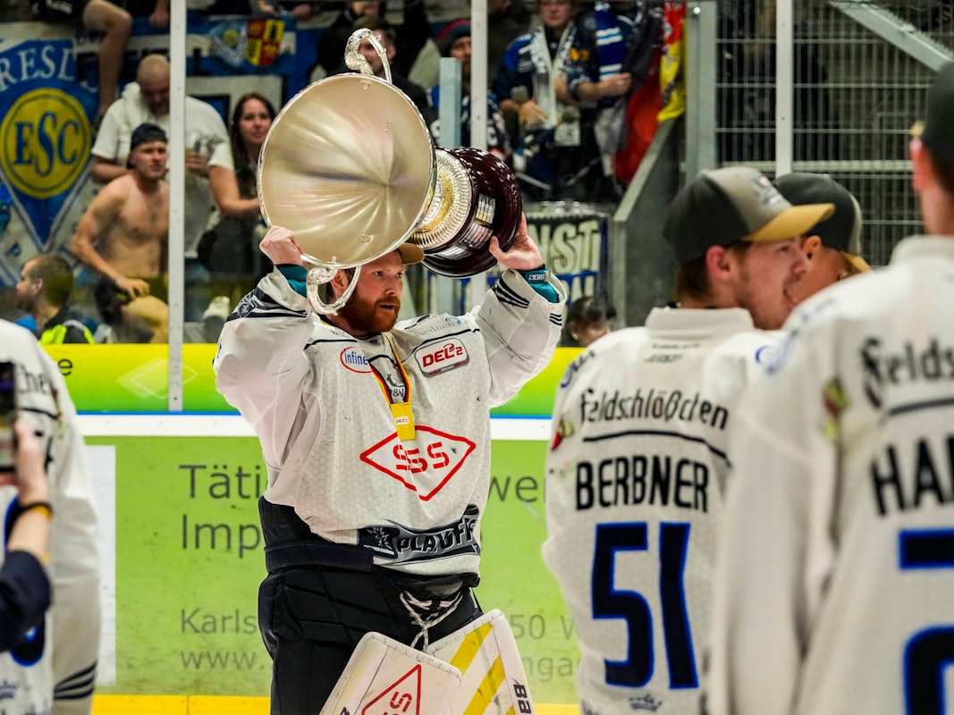 Danny aus den Birken hält den Meisterpokal der DEL2 nach oben.