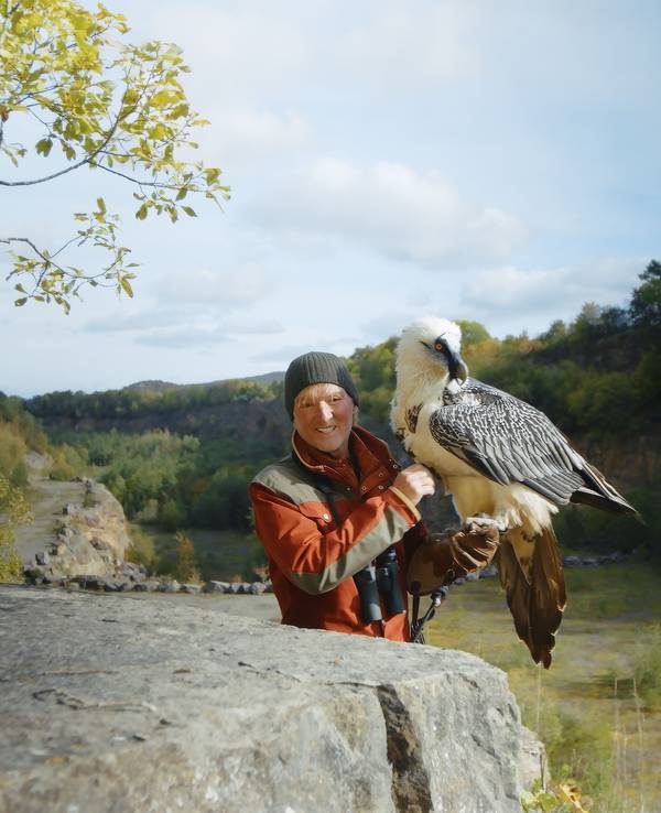 Andreas Kieling steht mit einem Bartgeier in einem Steinbruch in der Eifel.