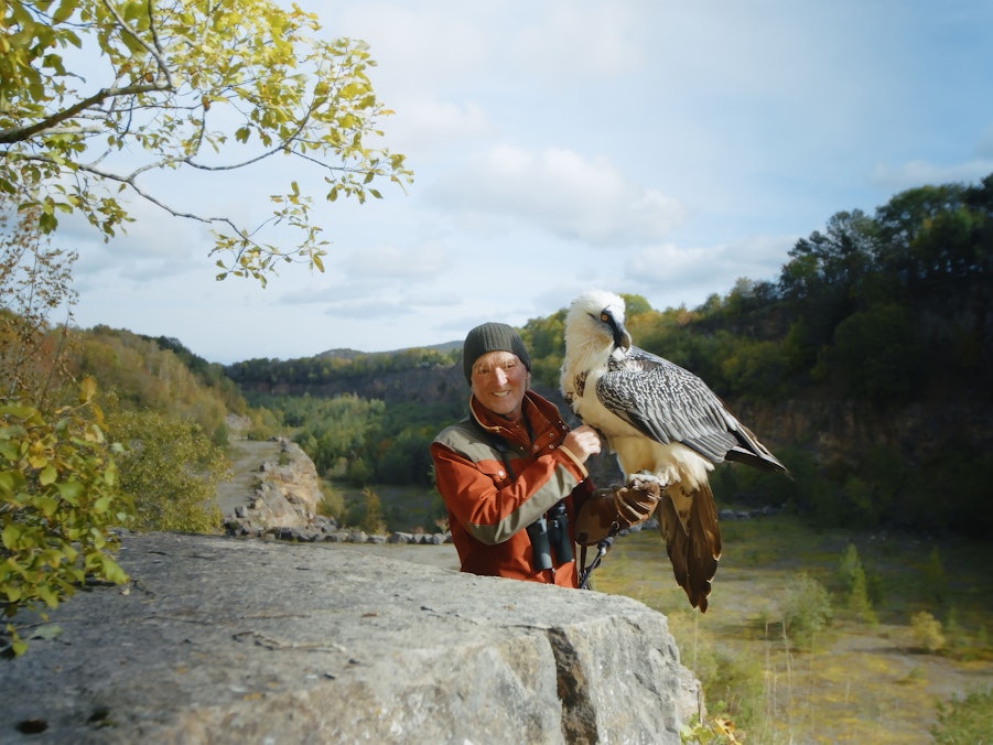 Andreas Kieling steht mit einem Bartgeier in einem Steinbruch in der Eifel.