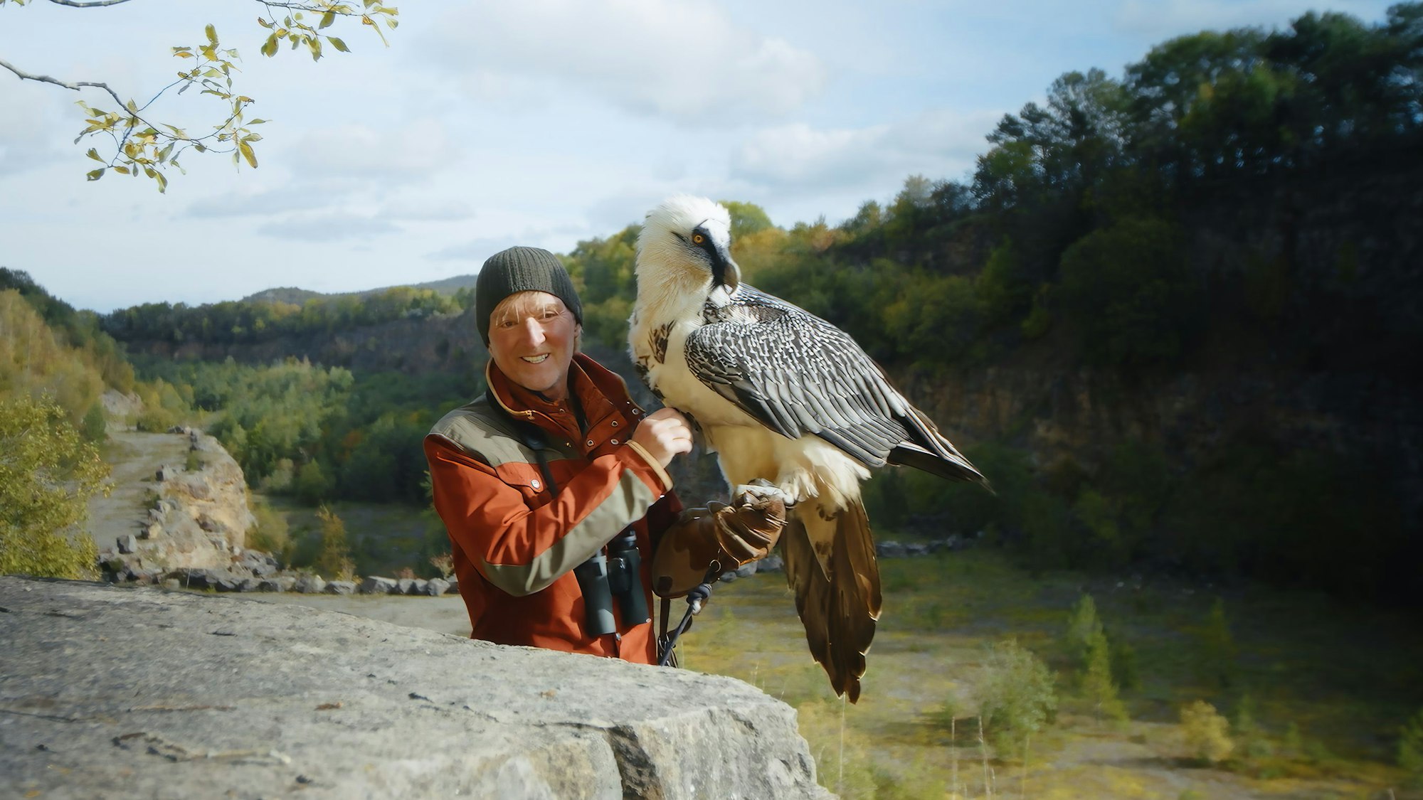 Andreas Kieling steht mit einem Bartgeier in einem Steinbruch in der Eifel.