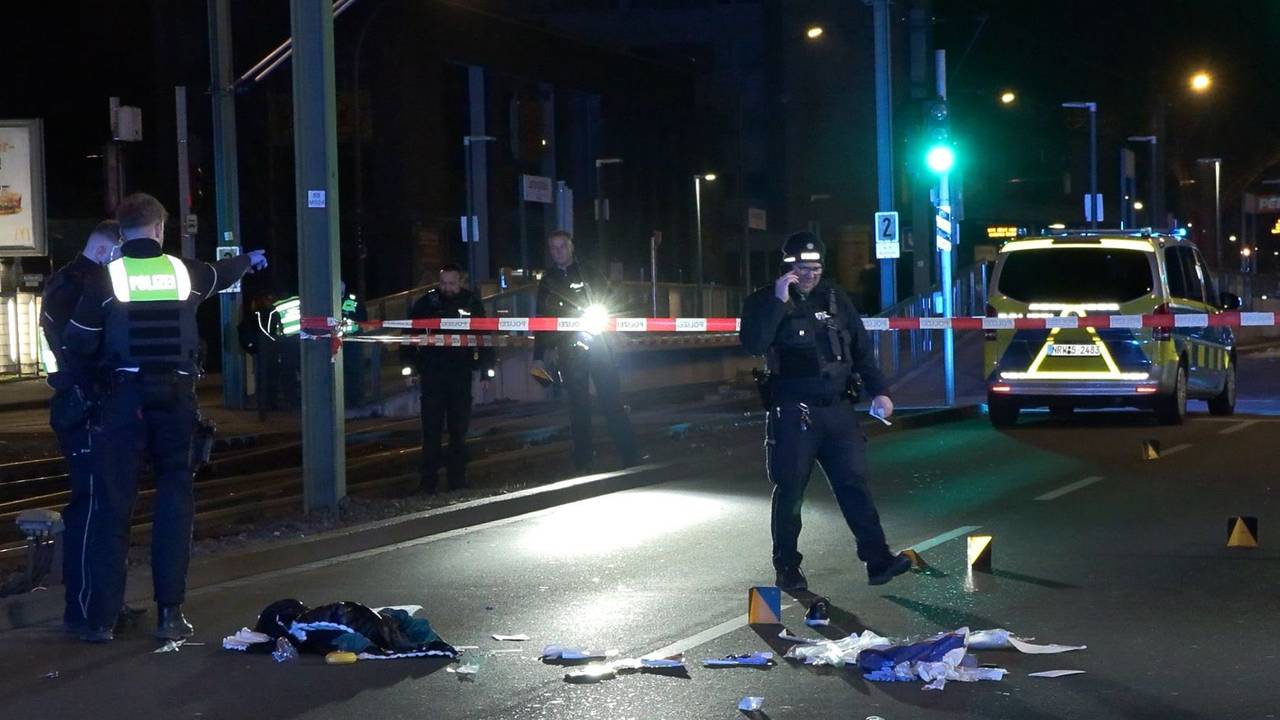 Einsatzkräfte der Polizei untersuchen einen mit Flatterband abgesperrten Tatort auf einer Straße.