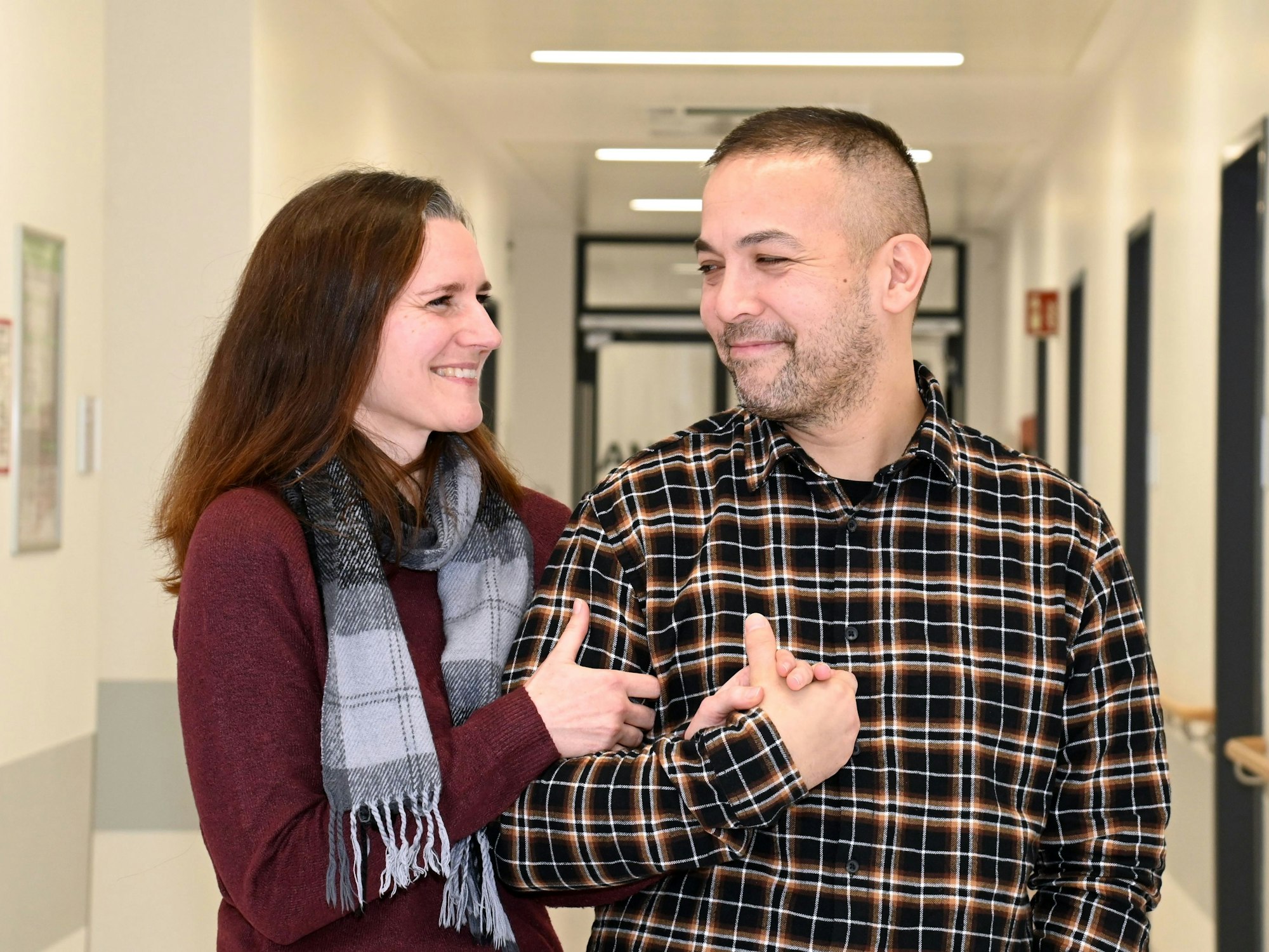 Ein Paar steht dicht beieinander und lächelt sich an.