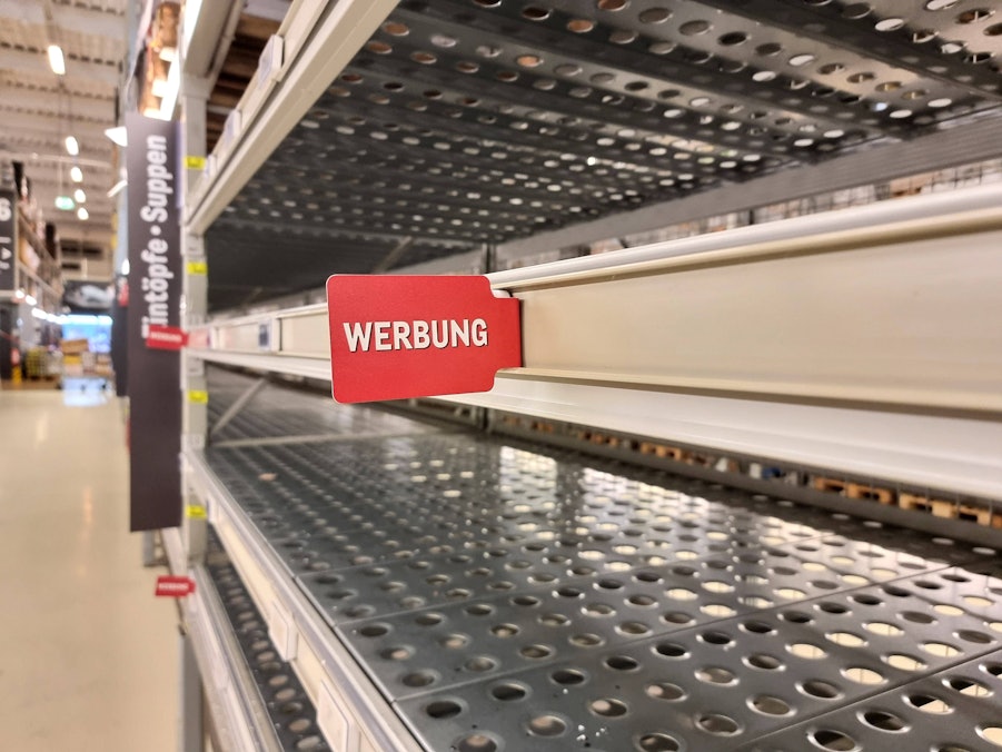 Leere Supermarktregale und ein Schild mit Werbung