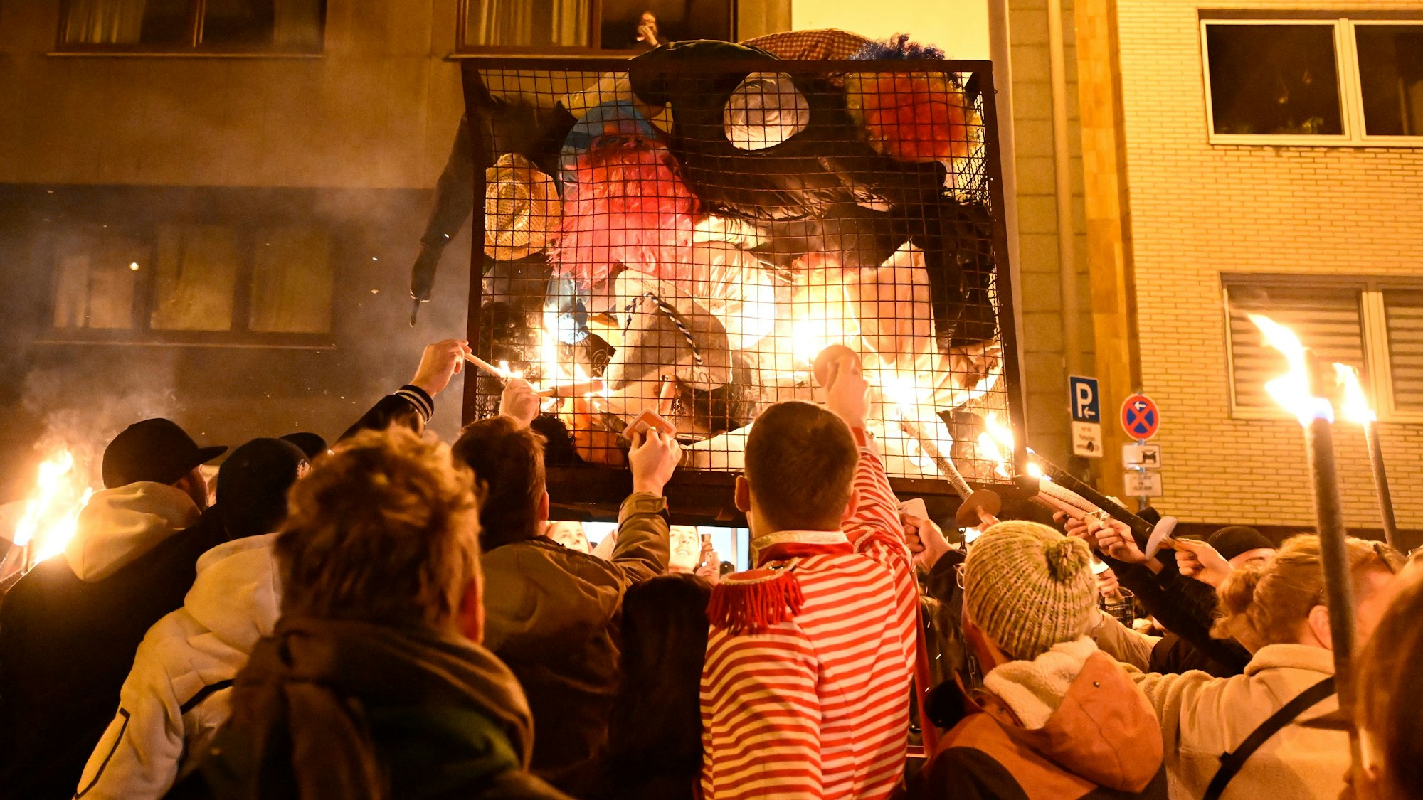 Karnevalisten zündeln ihre Nubbel in dem Gefängniskäfig an.