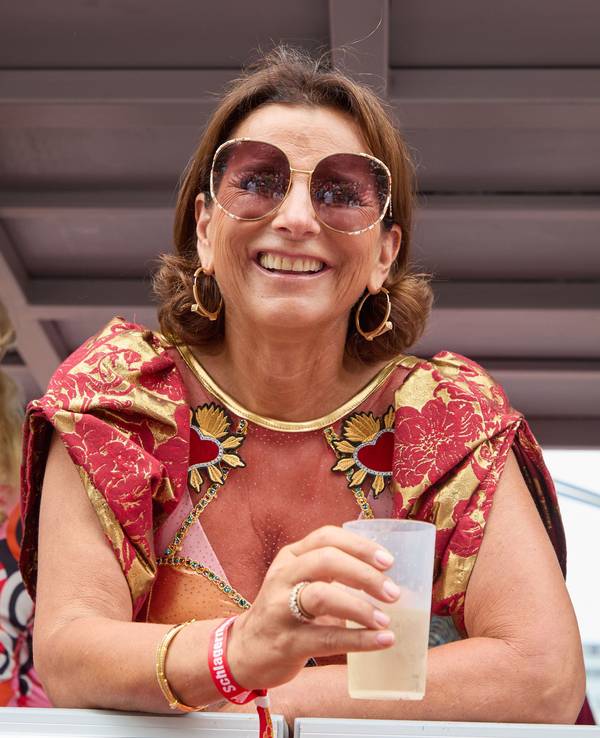 Claudia Obert lacht mit einem Dring in der Hand von einem Parade-Wagen.