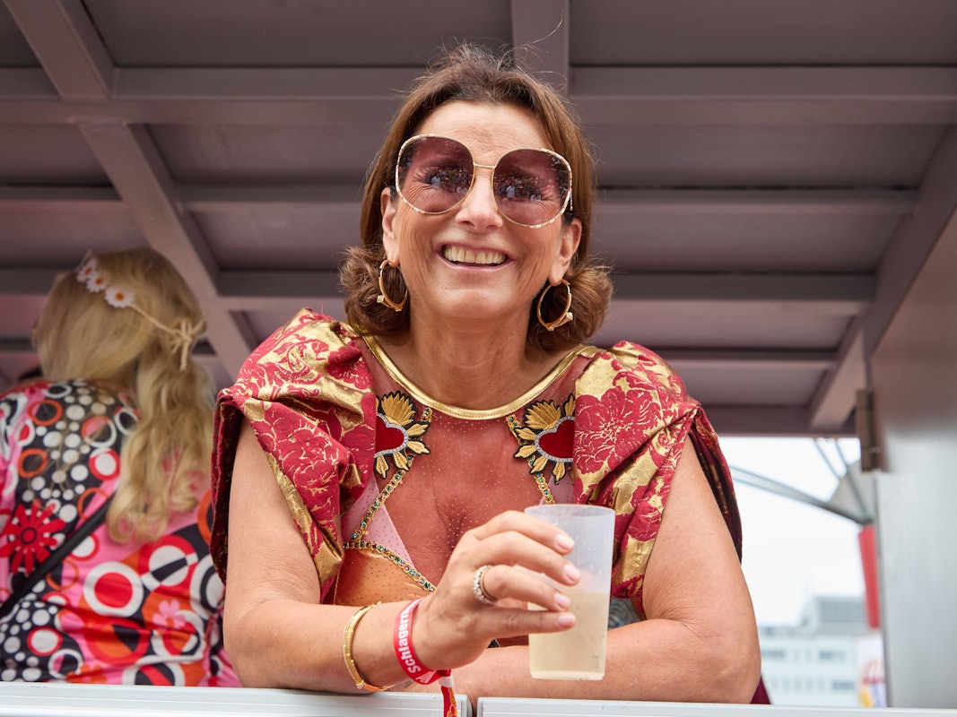 Claudia Obert lacht mit einem Dring in der Hand von einem Parade-Wagen.