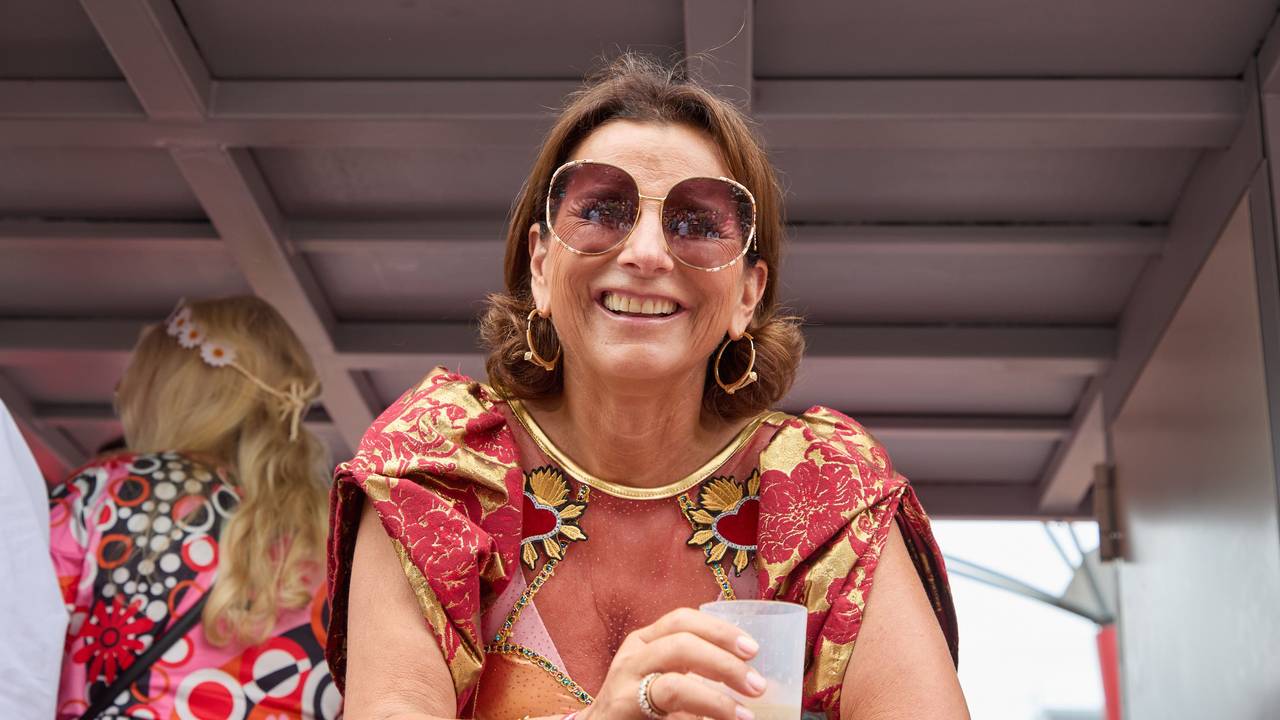 Claudia Obert lacht mit einem Dring in der Hand von einem Parade-Wagen.