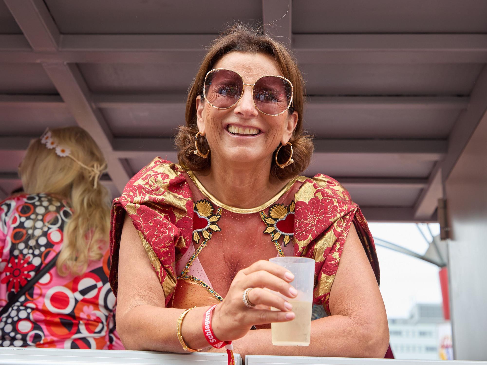 Claudia Obert lacht mit einem Dring in der Hand von einem Parade-Wagen.