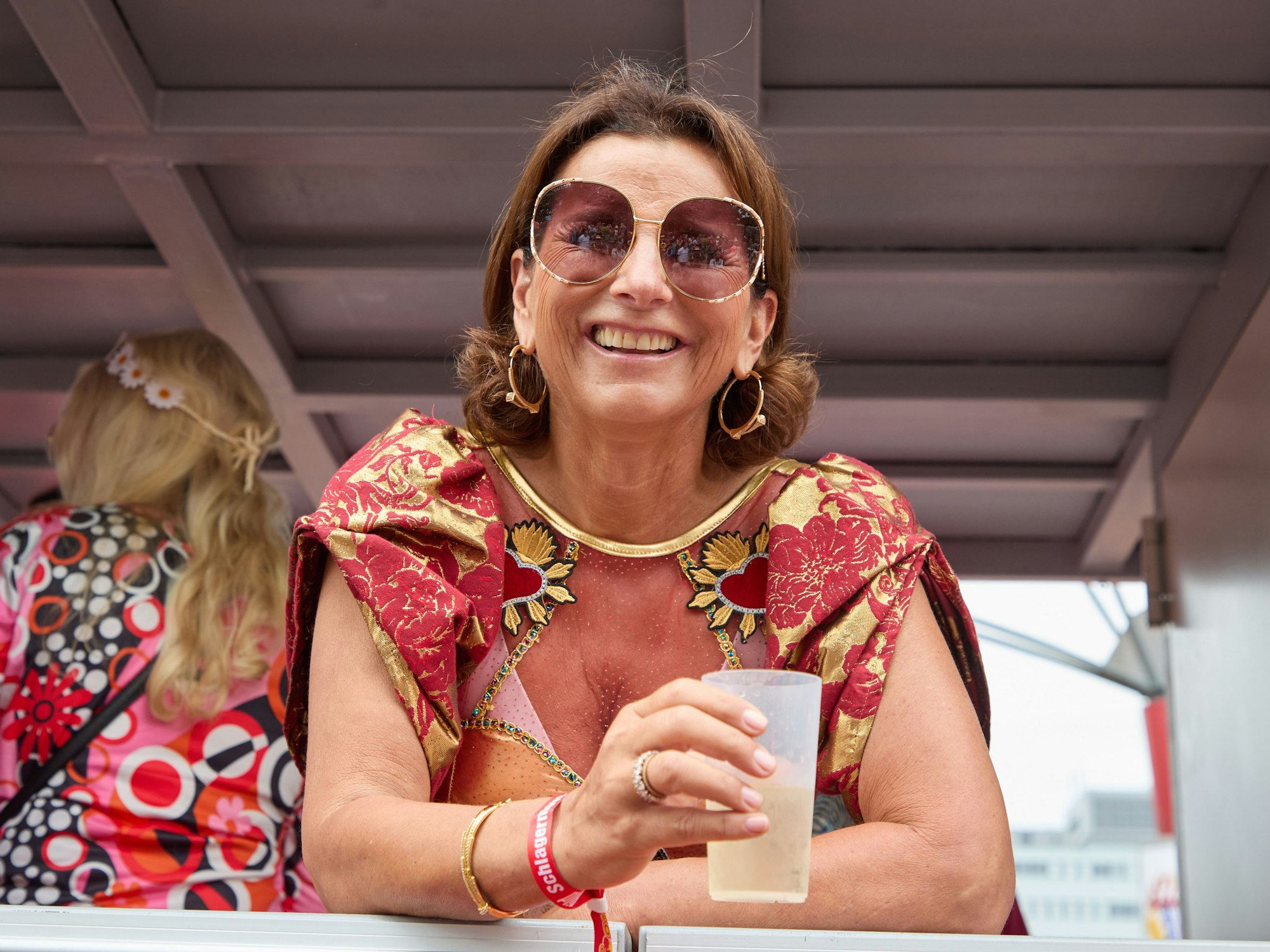 Claudia Obert lacht mit einem Dring in der Hand von einem Parade-Wagen.