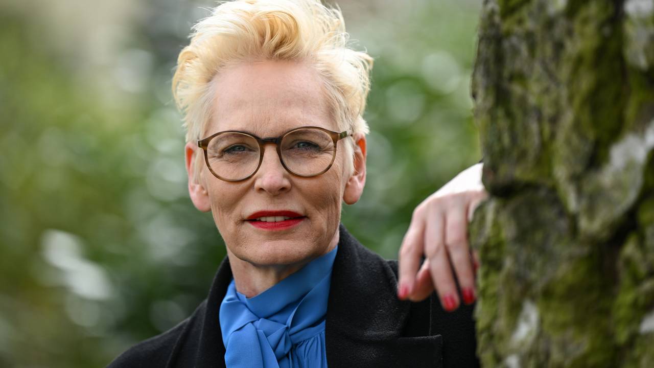 Bärbel Schäfer schaut an einen Baum gelehnt in die Kamera.