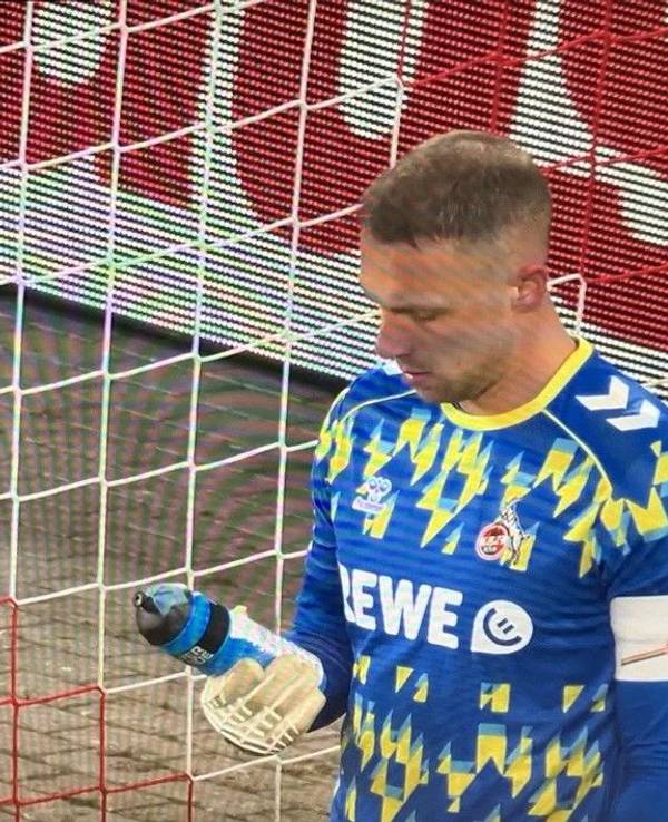 Marvin Schwäbe guckt auf seine Trinkflasche, auf der ein Zettel befestigt ist.