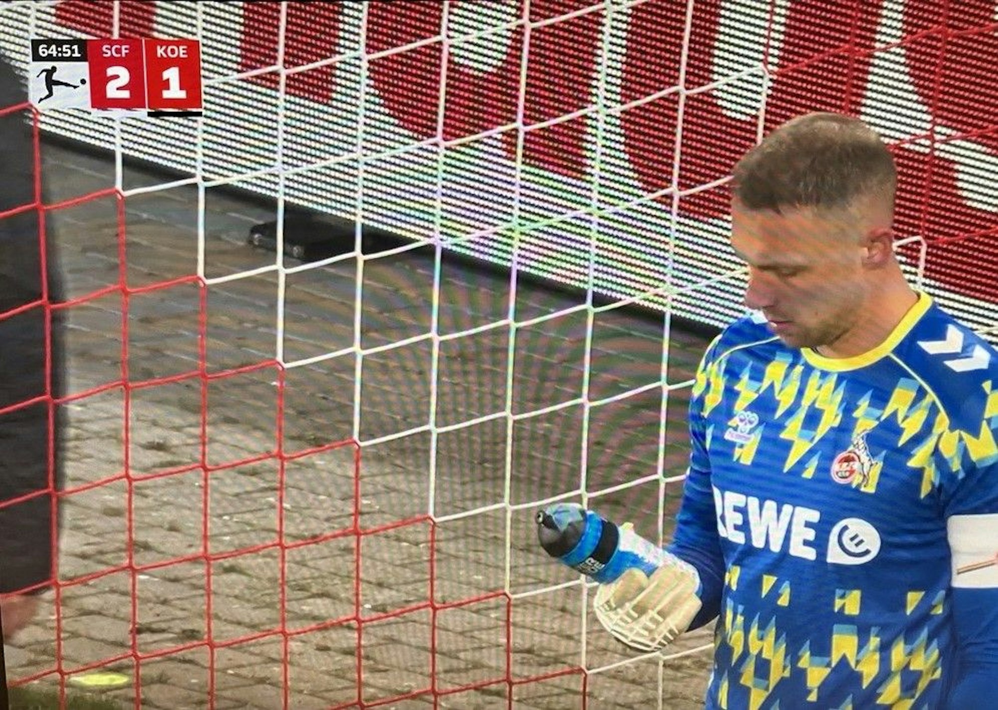 Marvin Schwäbe guckt auf seine Trinkflasche, auf der ein Zettel befestigt ist.