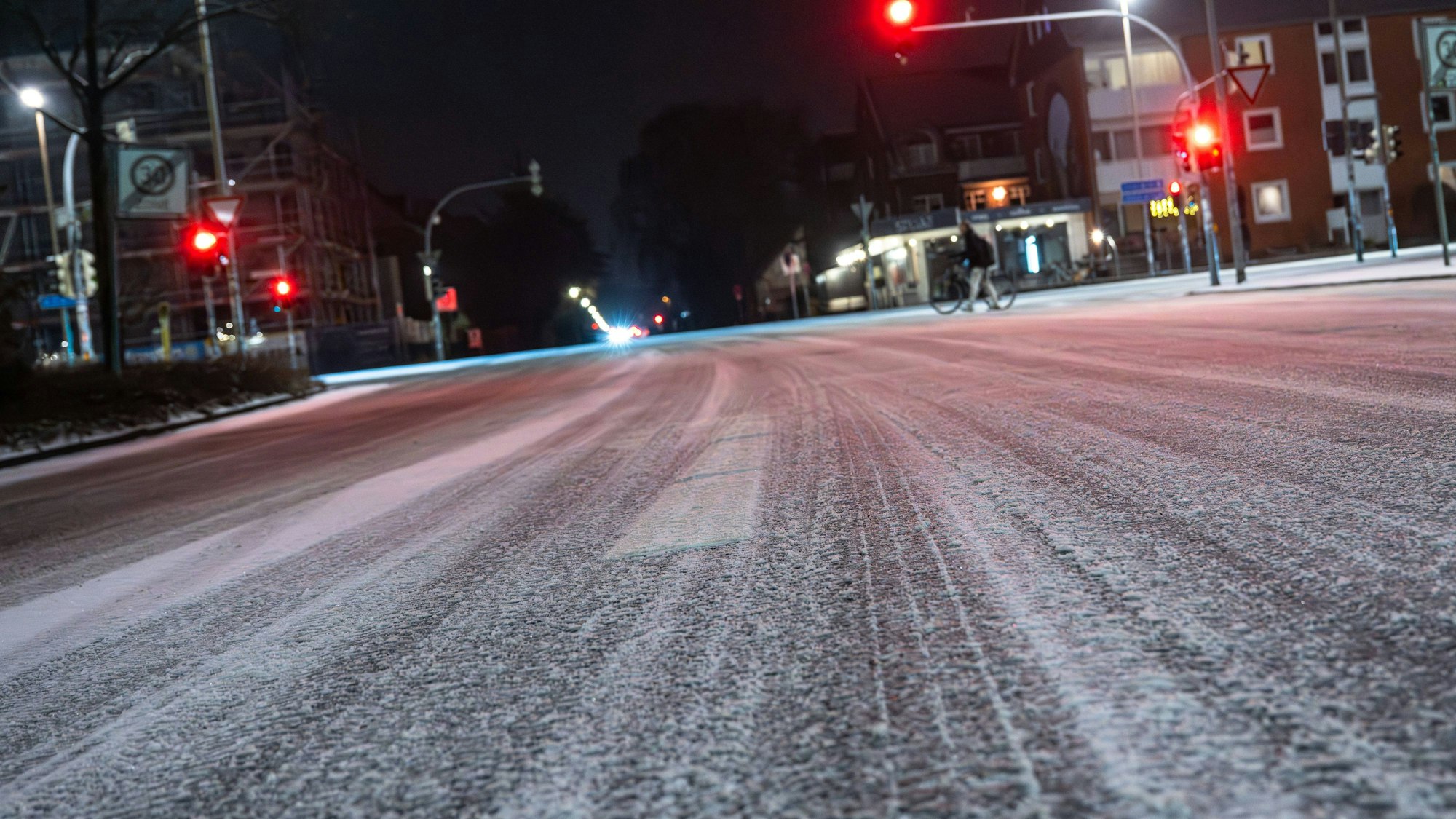 Glatte, verschneite Kreuzung bei Nacht mit Lichtern