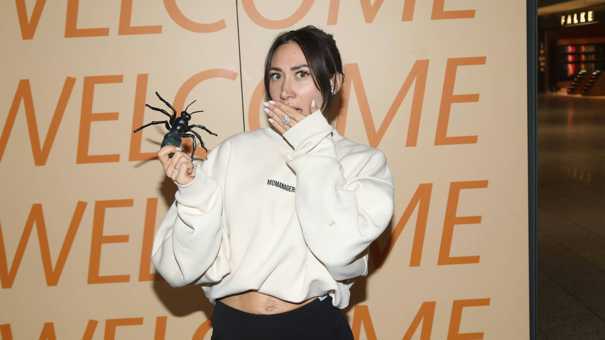 Samira Yavuz mit Spielzeugspinne und bedecktem Mund