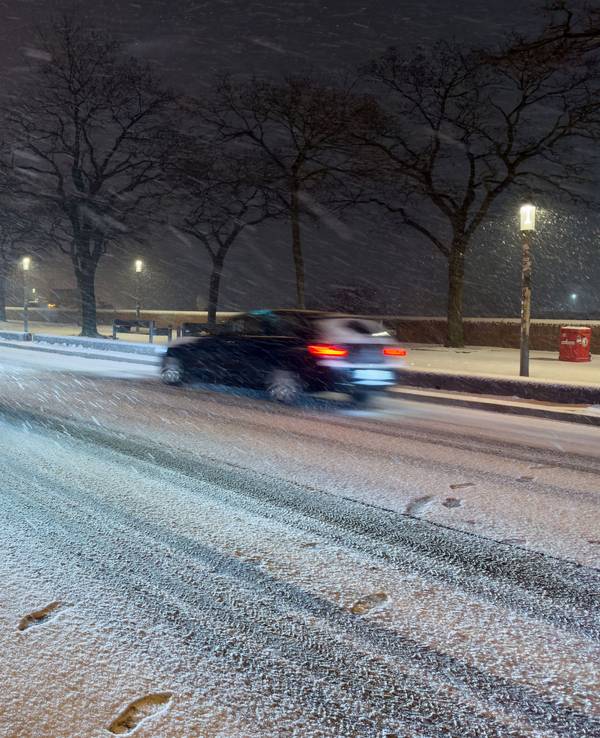 Schnee fällt am späten Samstagabend (24. Januar) auf einer Straße am Hafen in Hamburg.
